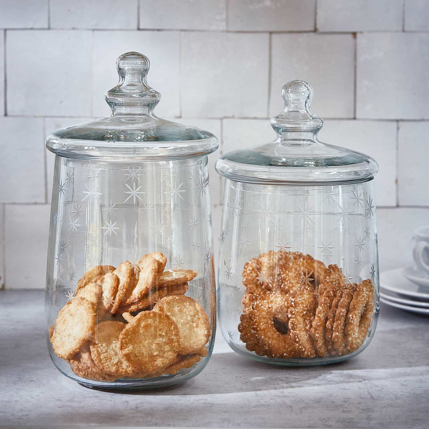 Glazen pot set van 2 Valerico Twee doorzichtige glazen potten met deksels, versierd met sterren, gevuld met koekjes