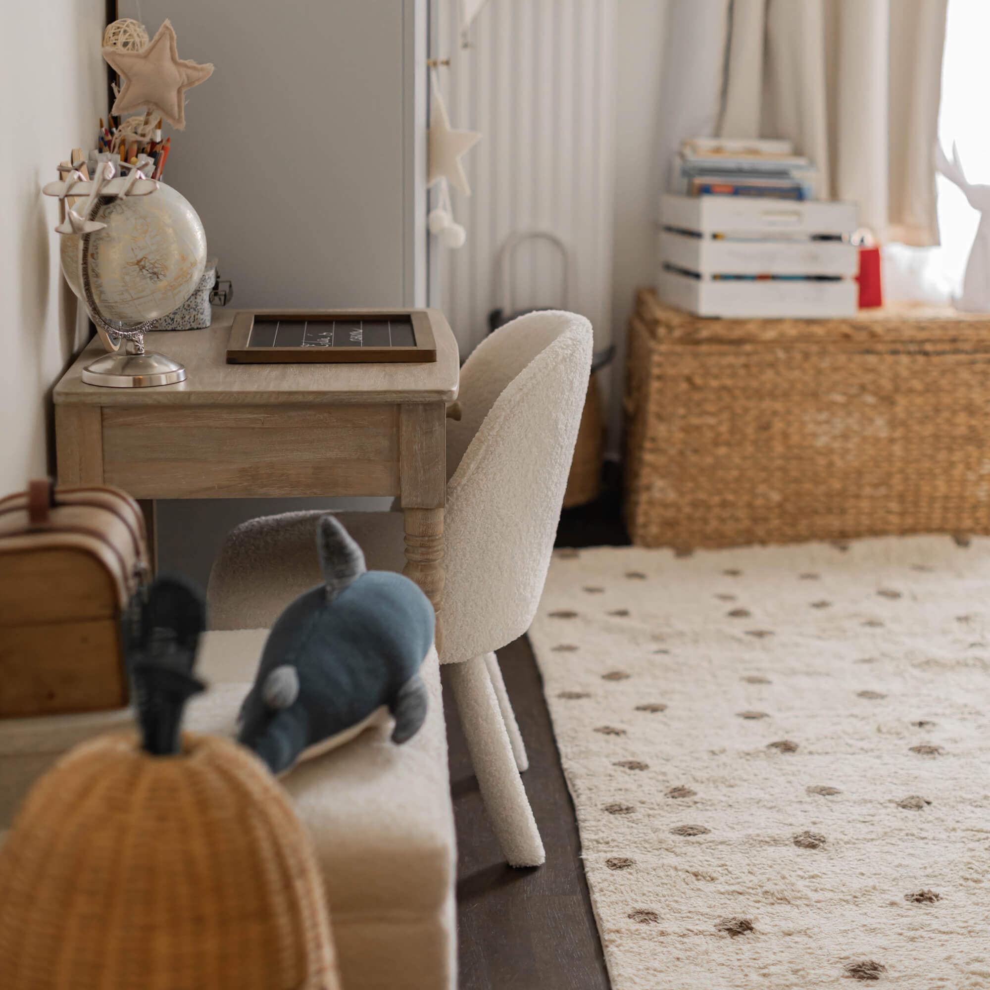Witte zachte stoel naast licht houten bureau in een gezellige kinderkamer