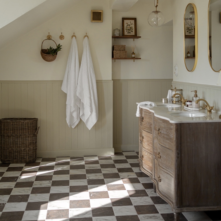 Badkamer met geruite marmeren vloer, houten kast en witte handdoeken aan haken