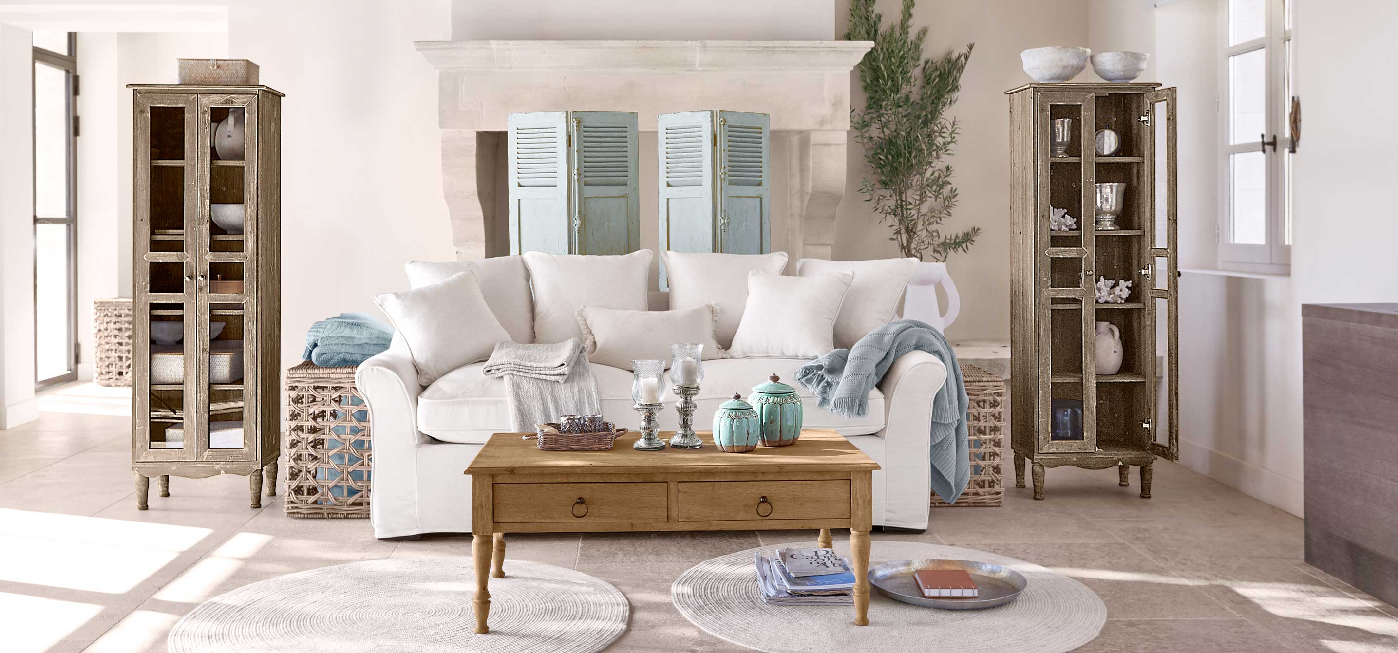 Gezellige woonkamer met witte bank, houten salontafel en twee vintage houten vitrinekasten