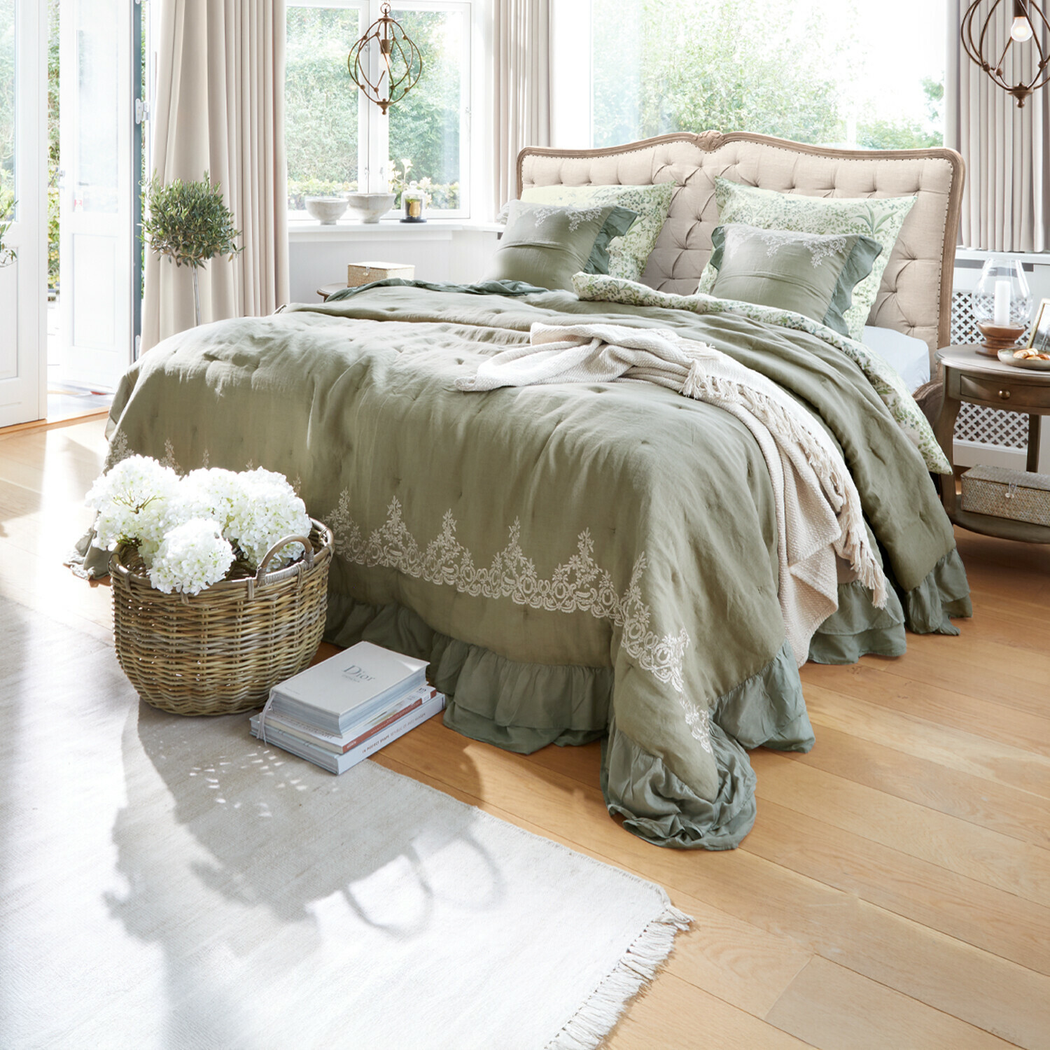 Slaapkamer met beige gestoffeerd hoofdeinde en groene linnen beddengoed met borduurwerk