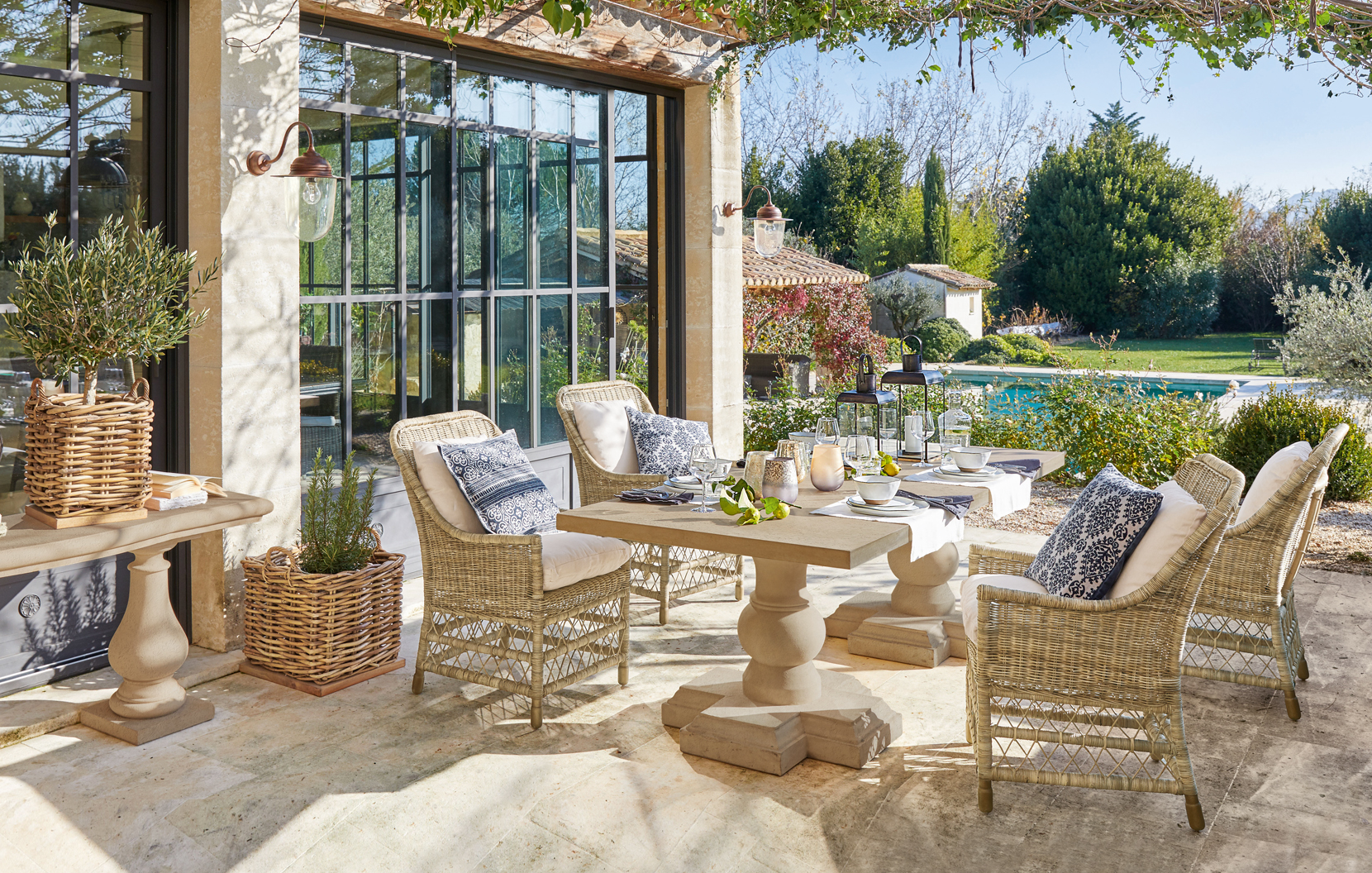 Gezellig terras met rotanmeubels en stenen tafel in mediterrane stijl met uitzicht op het zwembad