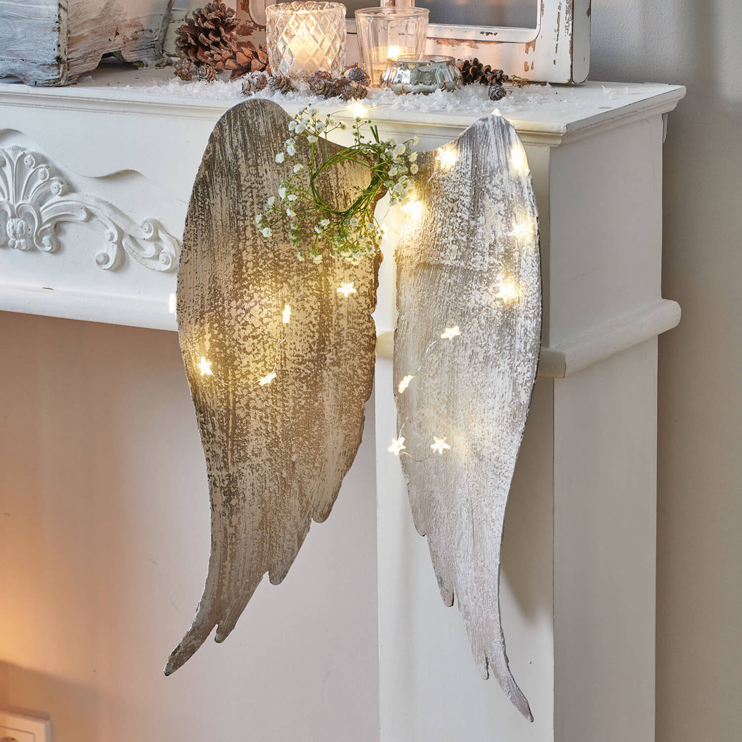Decoratieve witte houten engelenvleugels met LED-lichtjes en groene takjes voor aan de muur