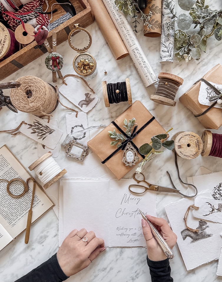 Handgemaakte kerstkaart met natuurlijke versieringen en verpakkingsmaterialen op marmeren tafel