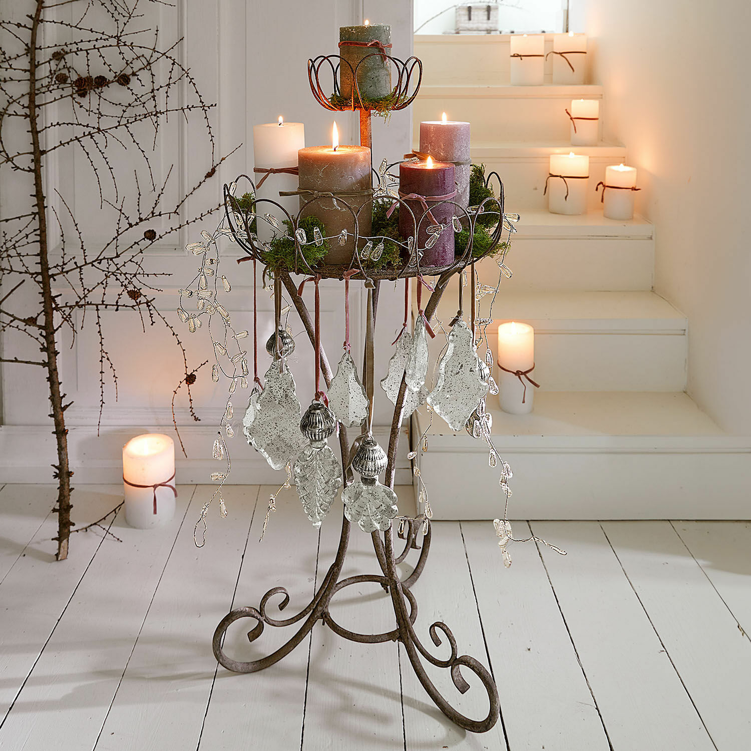 Metalen standaard met decoraties en kaarsen in natuurlijke kleuren op witte vloer en trap