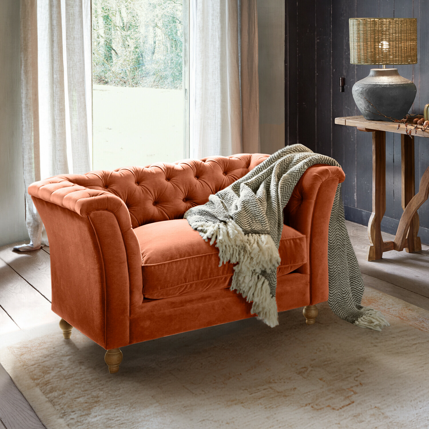 Bank Clères Oranje fluwelen Chesterfield-bank met grijze deken in gezellige woonkamer met lamp en houten tafel
