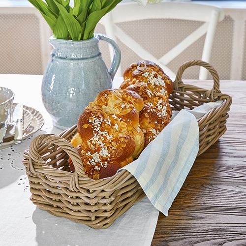 Rieten broodmand met handvatten en linnen doek op houten tafel in eetkamer