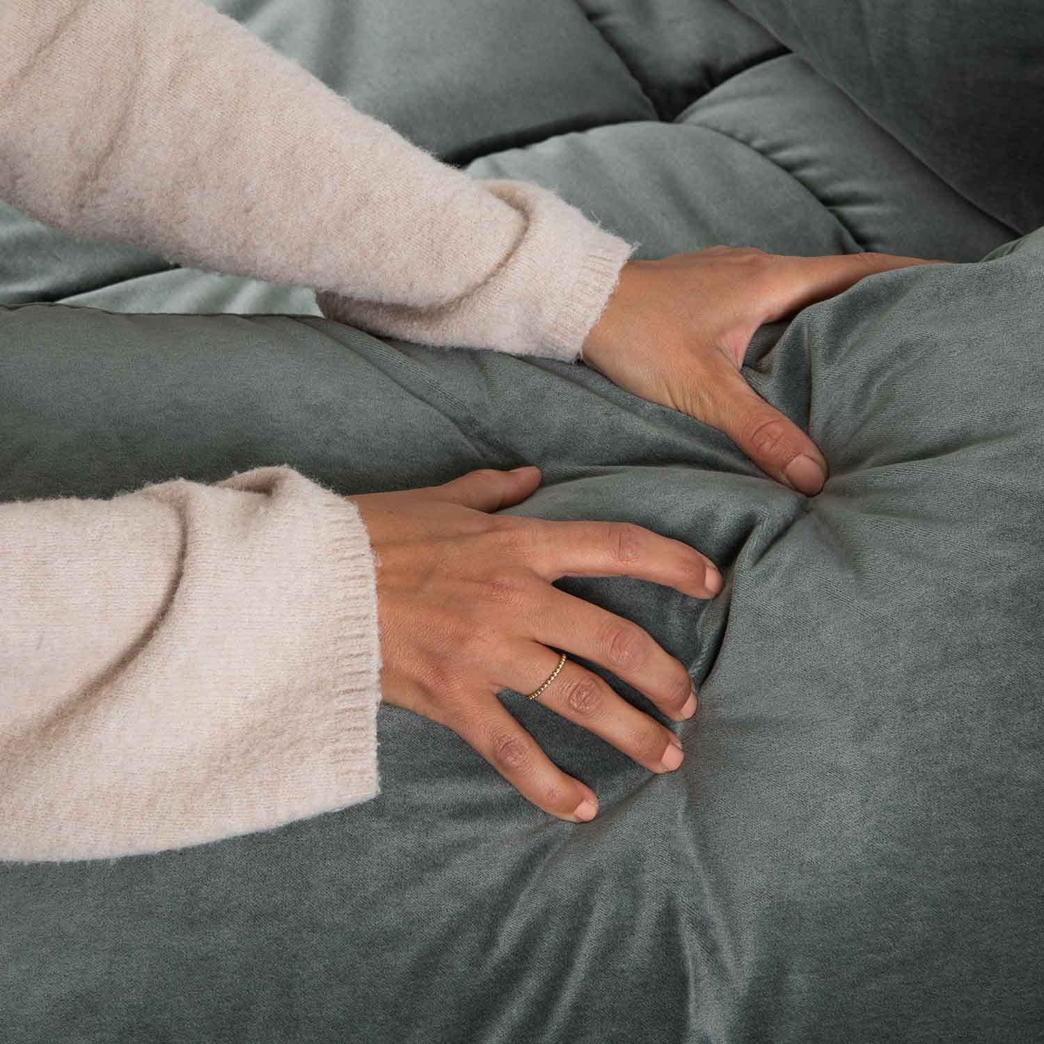 Handen die zacht groen fluwelen bekleding met knopen aanraken, comfortabele meubelstof