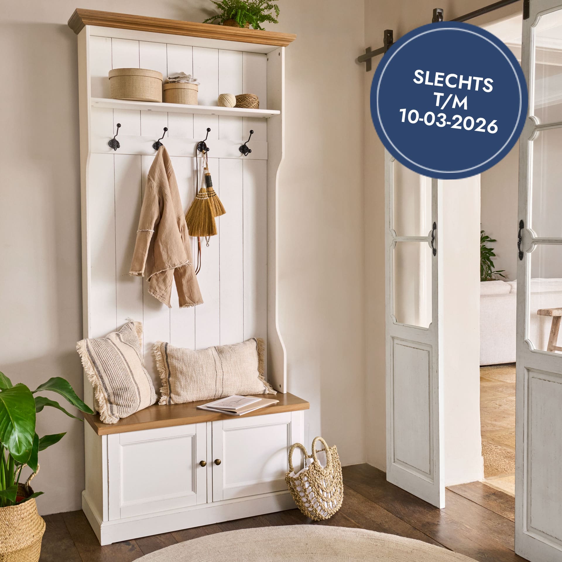 Witte houten kapstok met zitbank, haken en beige kussens, natuurlijke accessoires in lichte ruimte