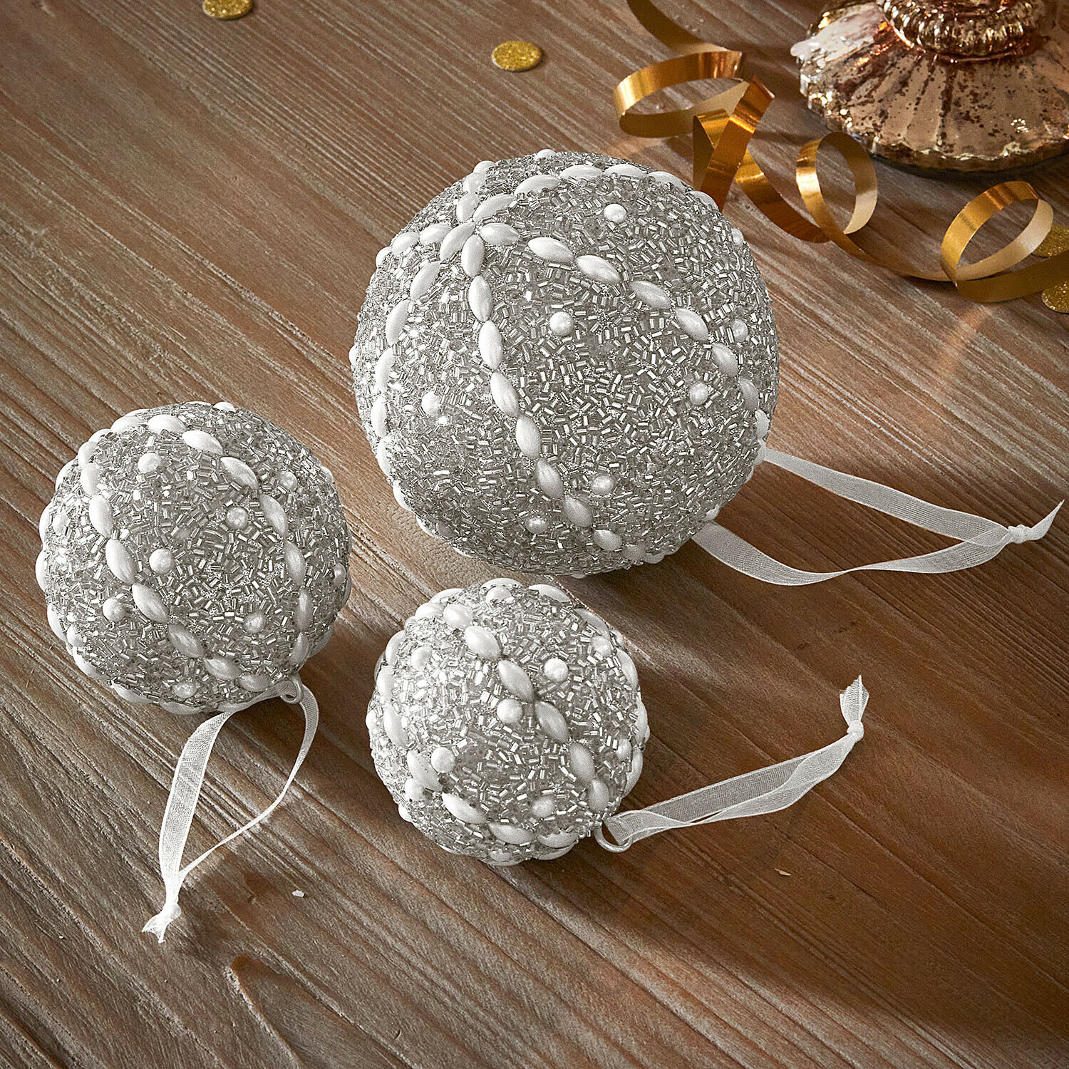Kerstbal set van 3 Maelvik Set van drie zilveren kerstballen met kralen en linten op houten tafel