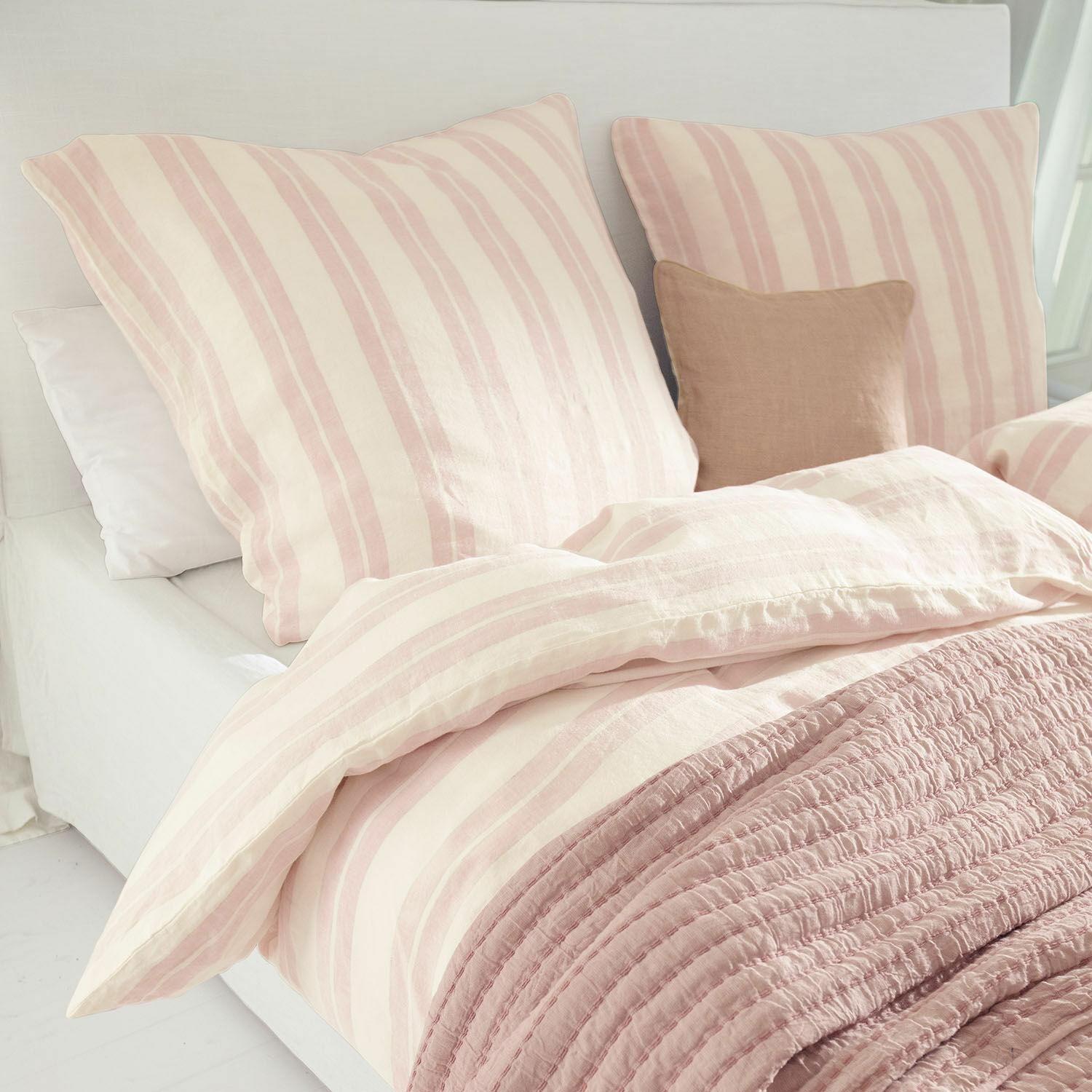 Beddengoed Dordogne Katoenen beddengoed met roze-crème strepen en zachte roze deken op een licht bed