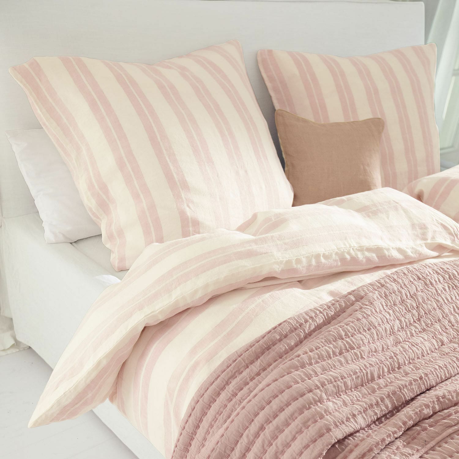 Beddengoed Dordogne Katoenen beddengoed met roze-crème strepen en zachte roze deken op een licht bed