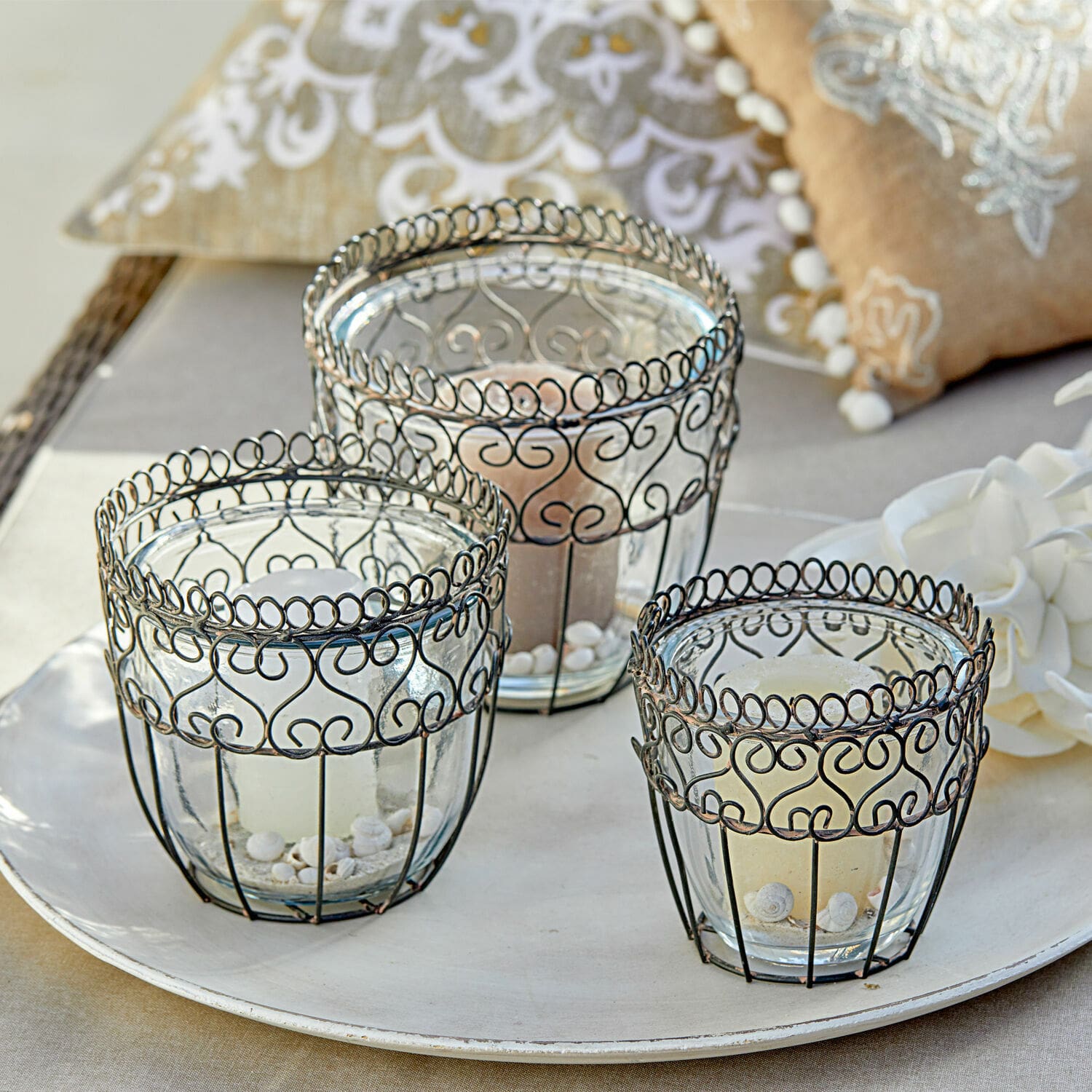 Set van drie glazen theelichthouders met zwart metalen frame en decoratieve patronen op een dienblad