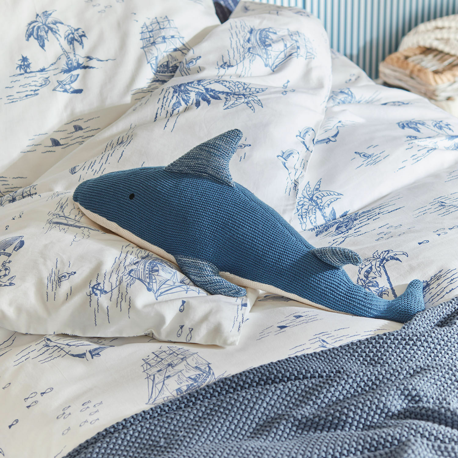 Knuffeldier Cheruboo Blauwe gebreide haai kussen op wit beddengoed met blauwe maritieme motieven