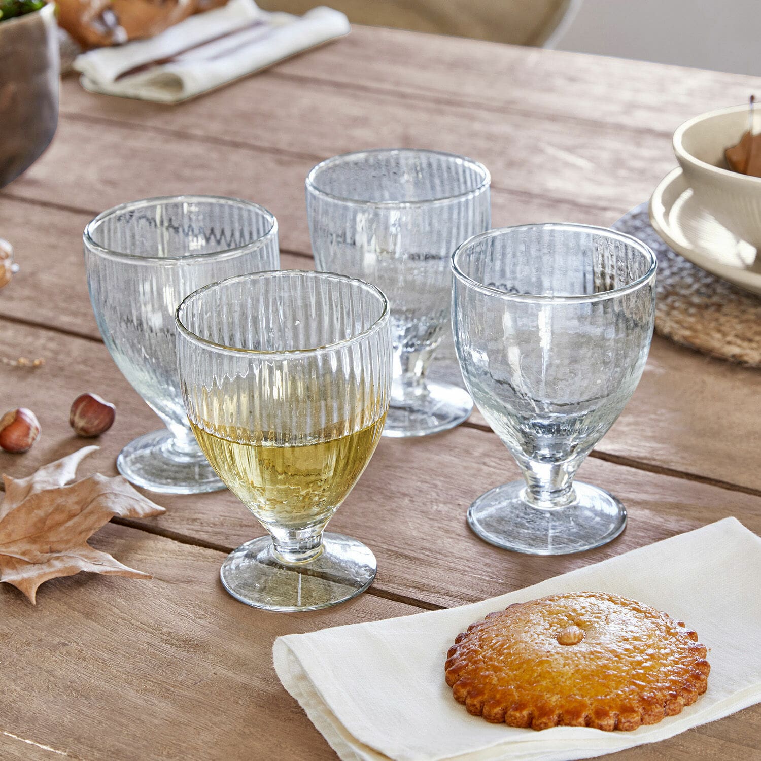 Glas set van 4 Laredo Set van vier doorzichtige geribbelde glazen op voet op houten tafel met koekje