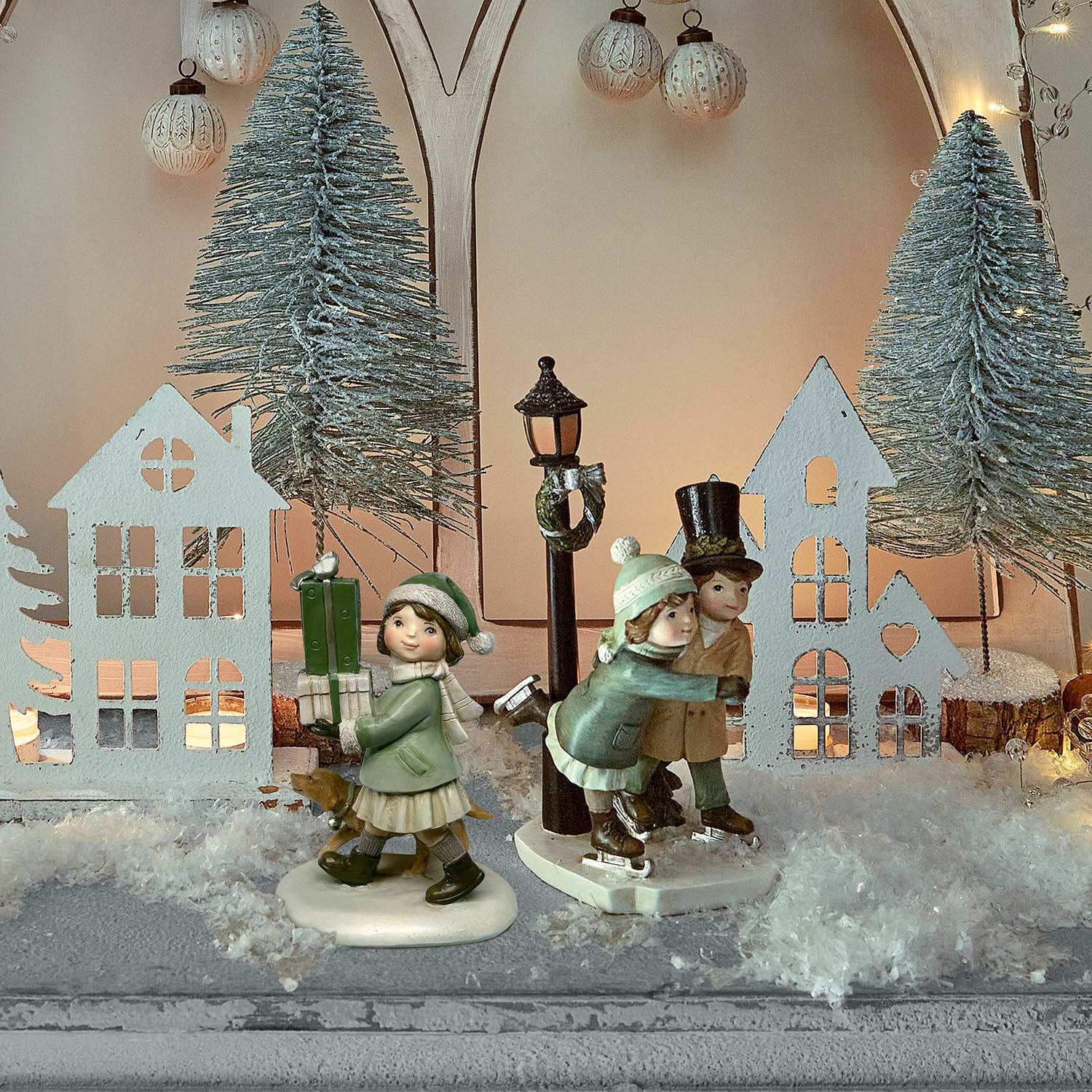 Winterse decoratie met kinderfiguren op schaatsen en huisjes in een besneeuwde kerstsetting