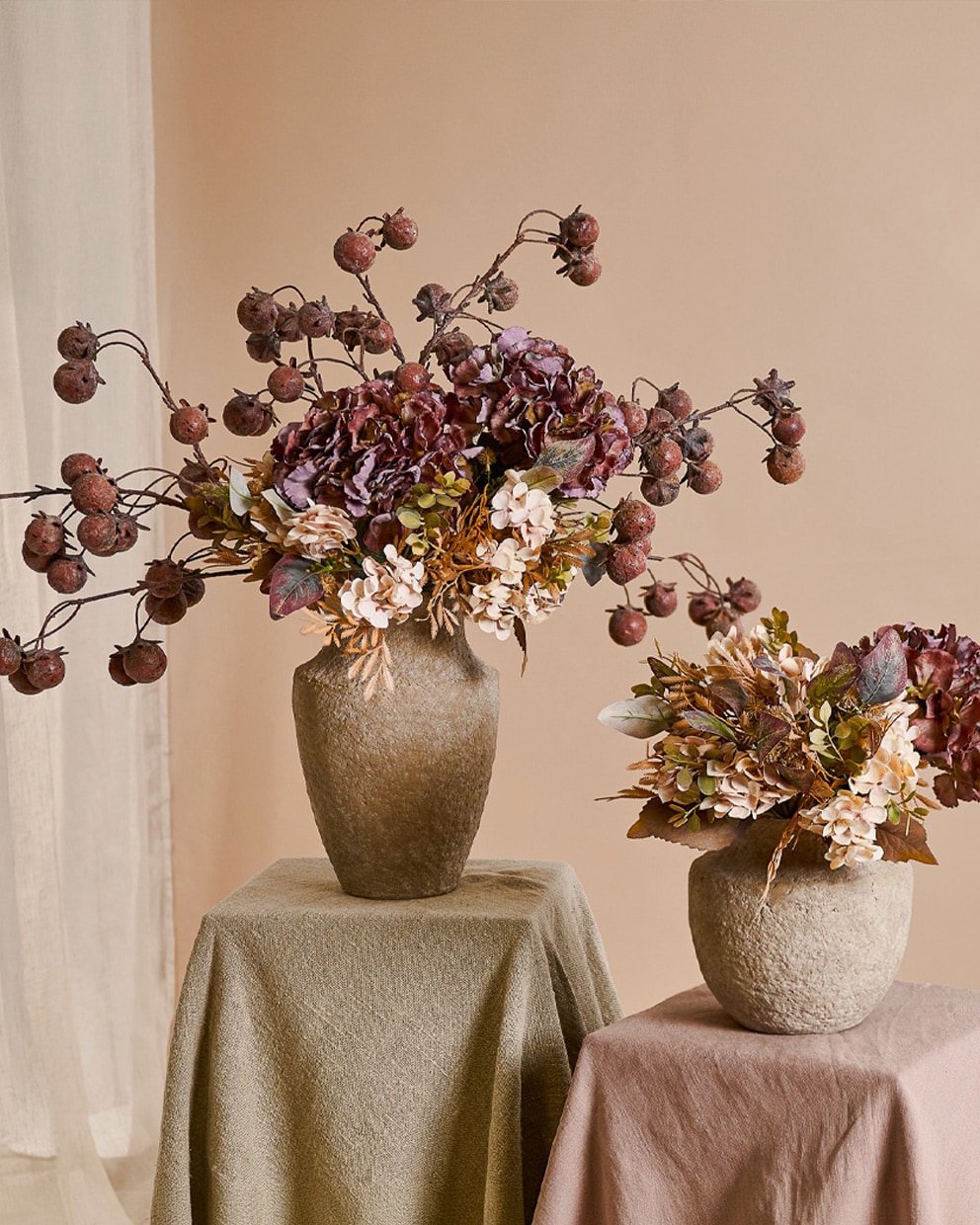 Twee stenen vazen met herfstbloemen en gedroogde vruchten in warme beige- en bruintinten voor interieurdecoratie