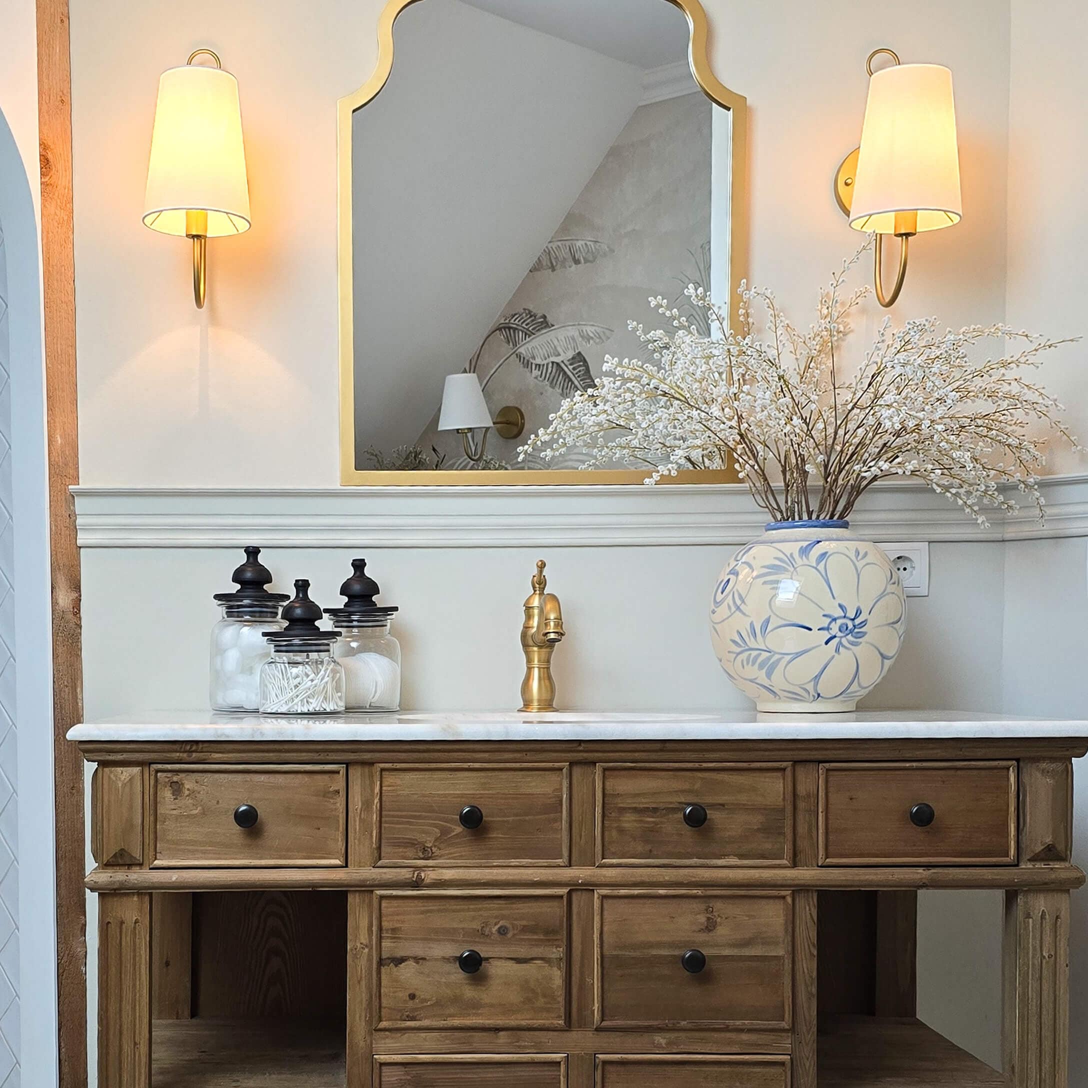 Houten dressoir met marmeren blad, gouden kraan en blauw-witte keramische vaas met bloemen