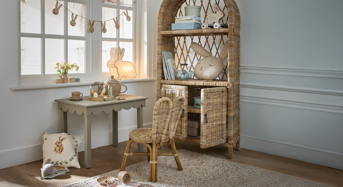Gezellige kinderkamerhoek met rotan kast, stoelen en konijnen decoraties in lichte kamer