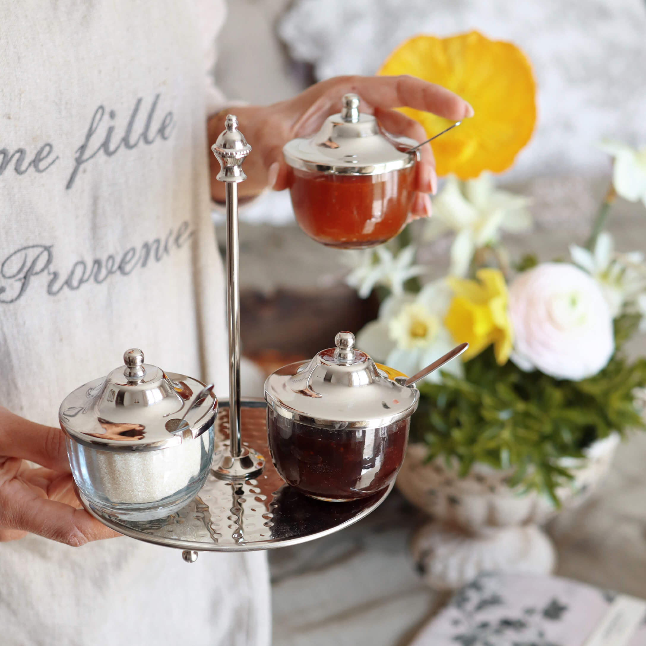 Glazen potten met metalen deksels op metalen dienblad, gevuld met jam en suiker