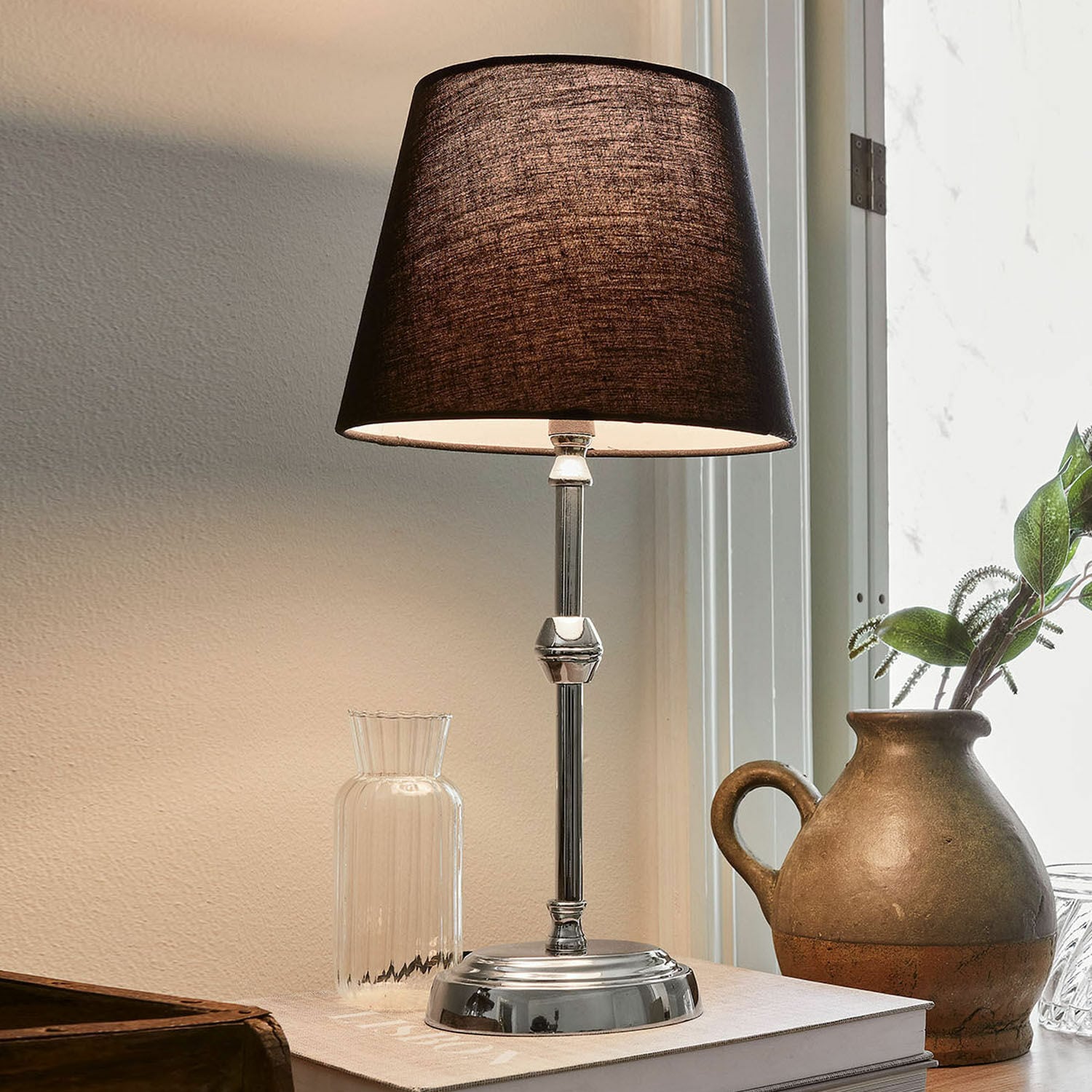 Tafellamp Luceau Elegante tafellamp met metalen voet en zwarte kap op bureau met decoratie