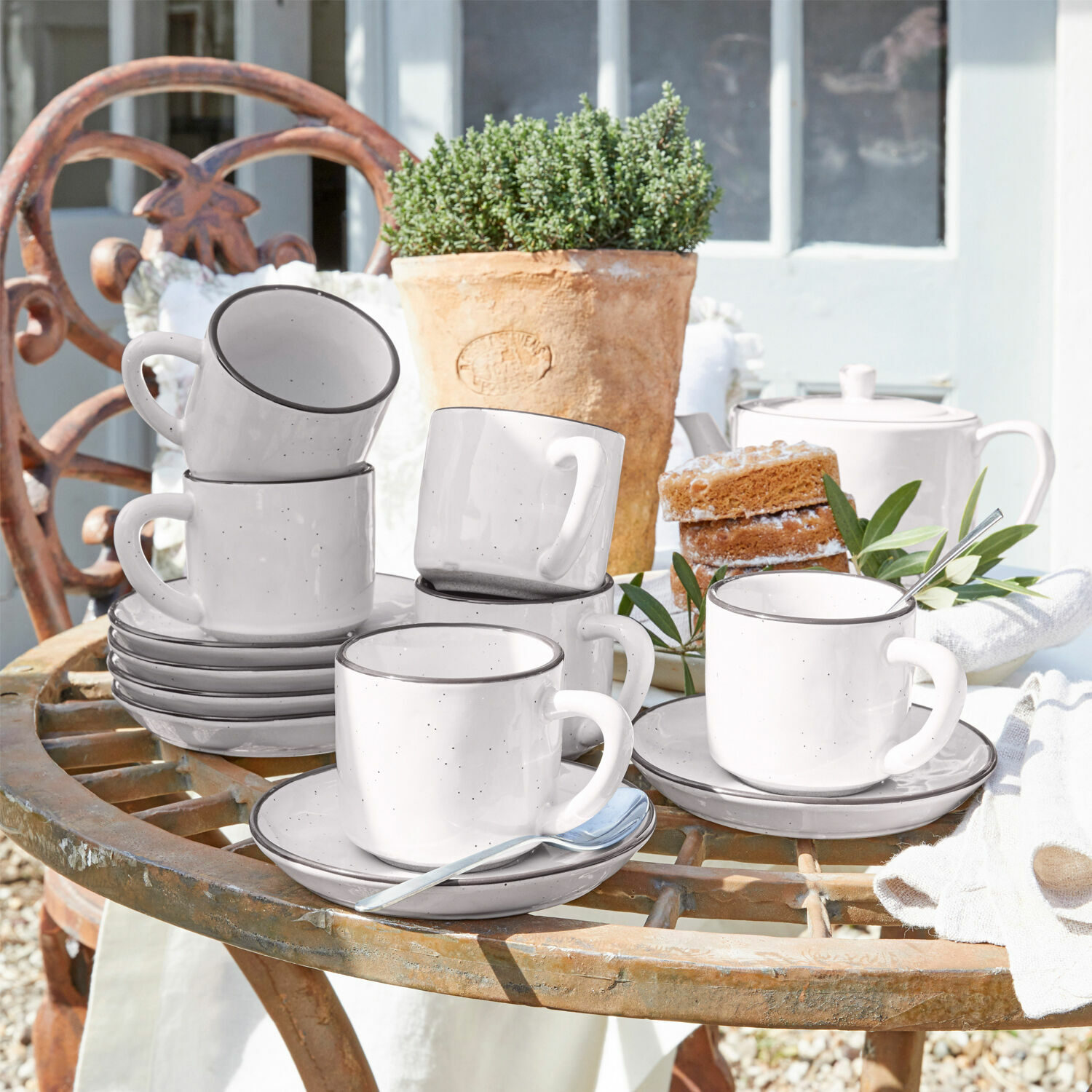 Kopje en schoteltje set van 6 Biarré Set witte keramische kopjes met schotels op rustieke tuintafel met taart en bloempot