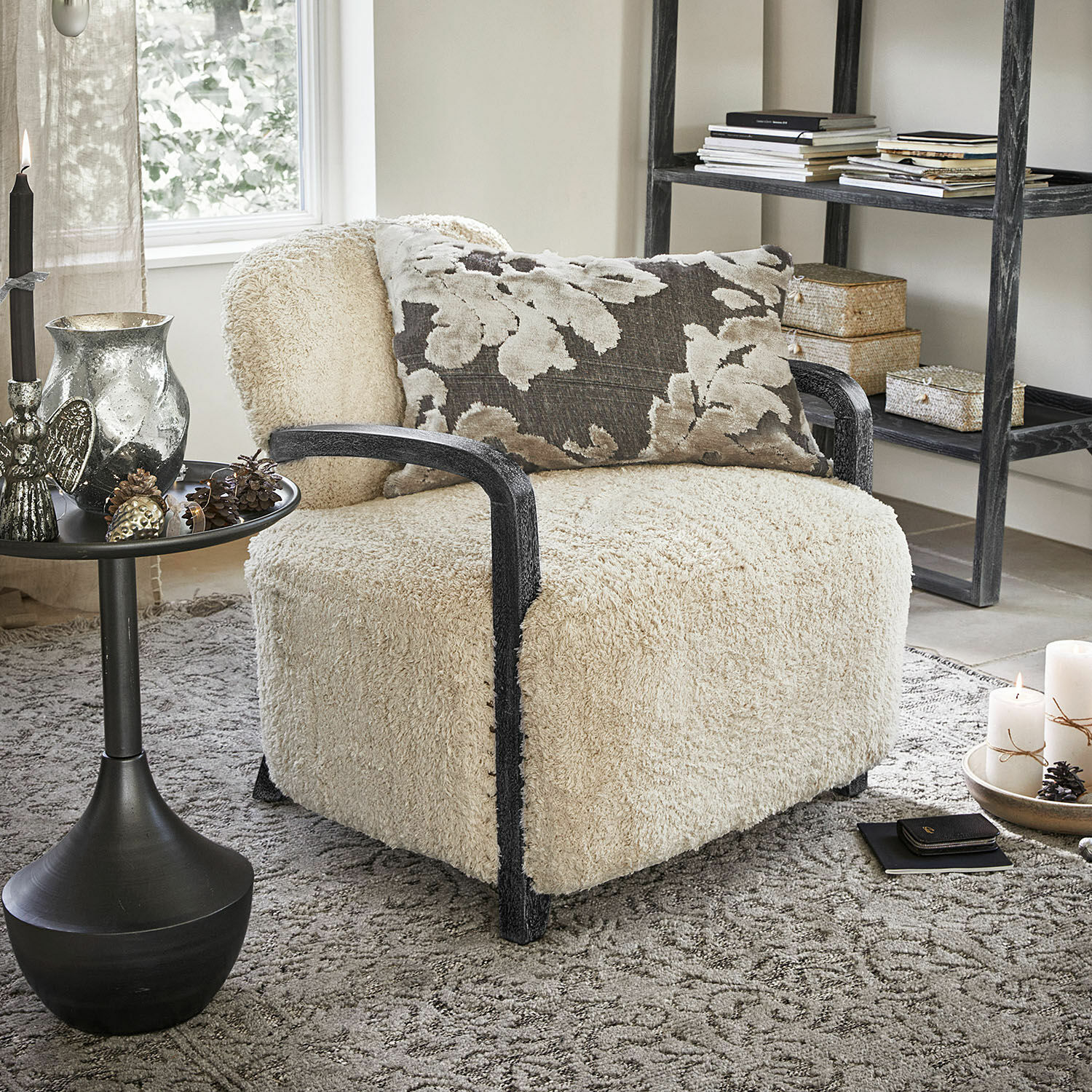 Fauteuil Roudaria Comfortabele fauteuil met crèmekleurige zachte bekleding en zwarte houten armleuningen in een gezellige woonkamer