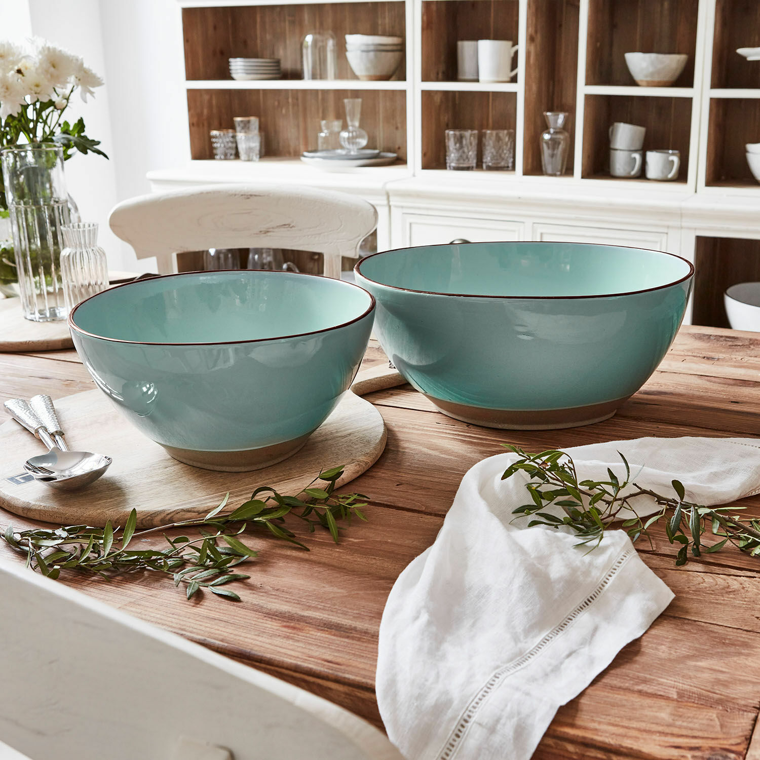 Set van twee turquoise keramische kommen op houten tafel met groene takken als decoratie