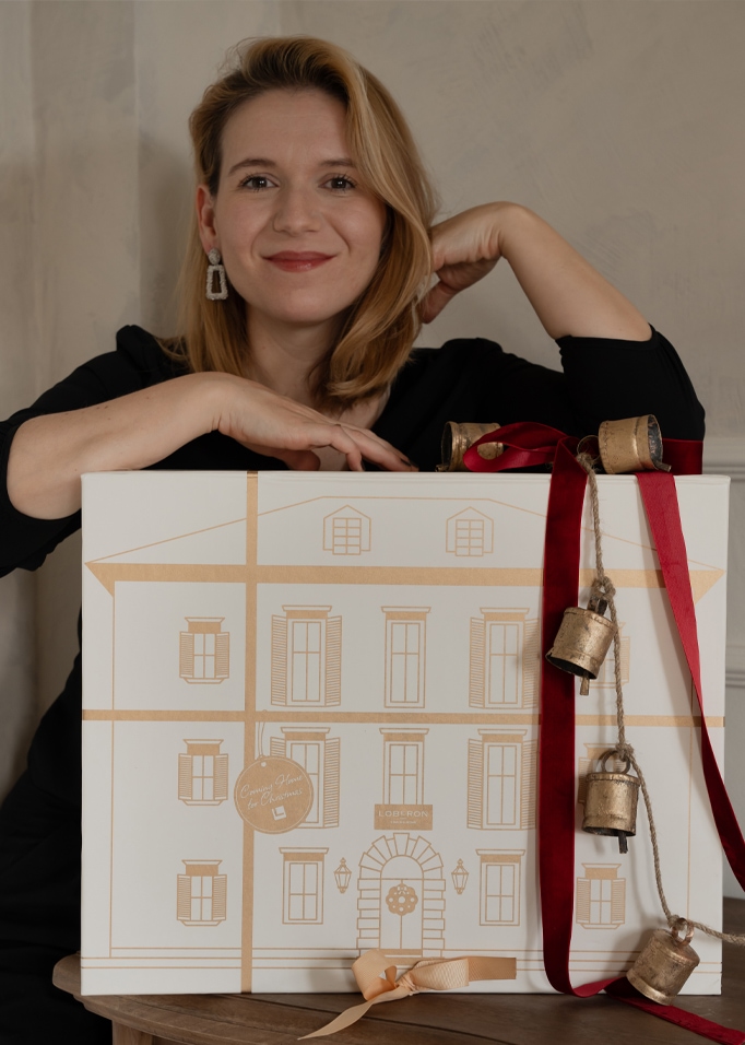 Vrouw met cadeauverpakking versierd met gouden huisafbeelding en rode bellen voor Kerstmis