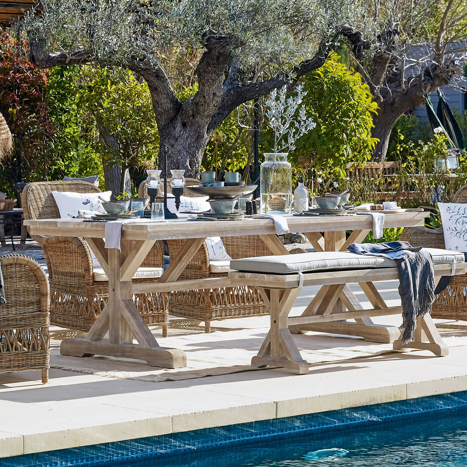 Tafel FSC®-100% Graslin Lichte houten tuintafel met rotan stoelen bij het zwembad in een natuurlijke buitenomgeving