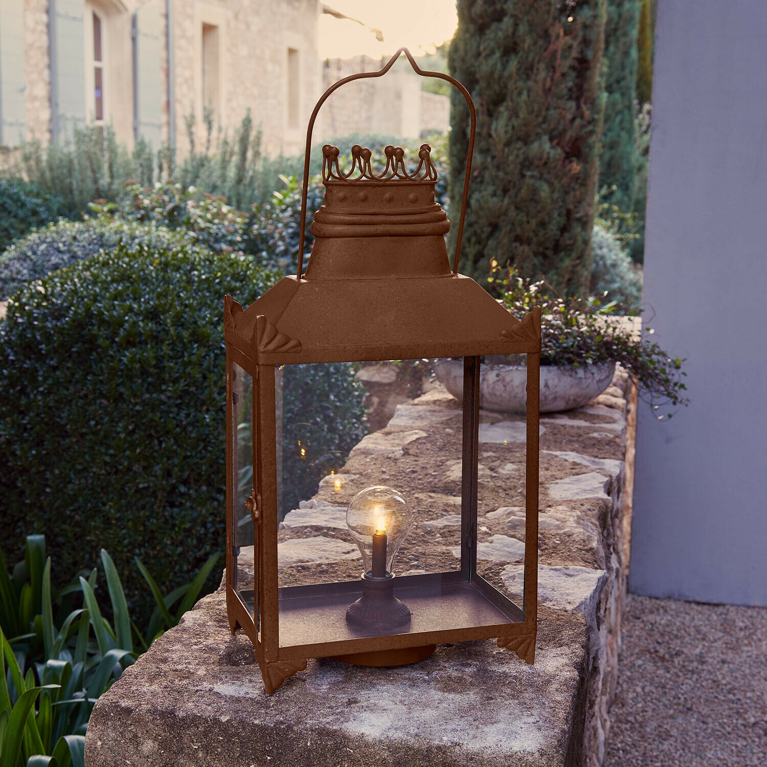 Rustieke metalen tuinlantaarn in roestkleur met helder glas en LED-lampje