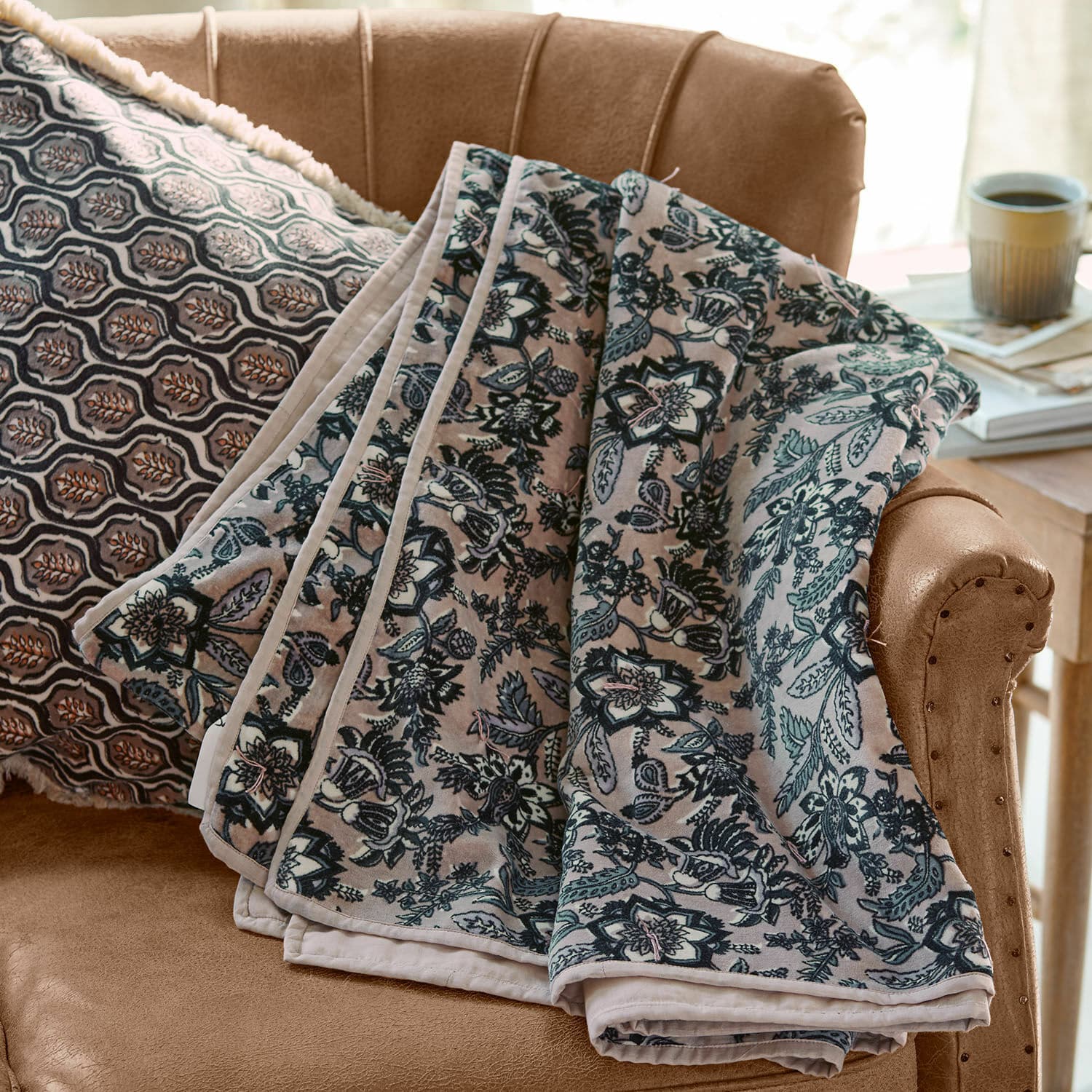 Plaid Elarion Zachte deken met grijs bloemenpatroon op beige bank met decoratief kussen