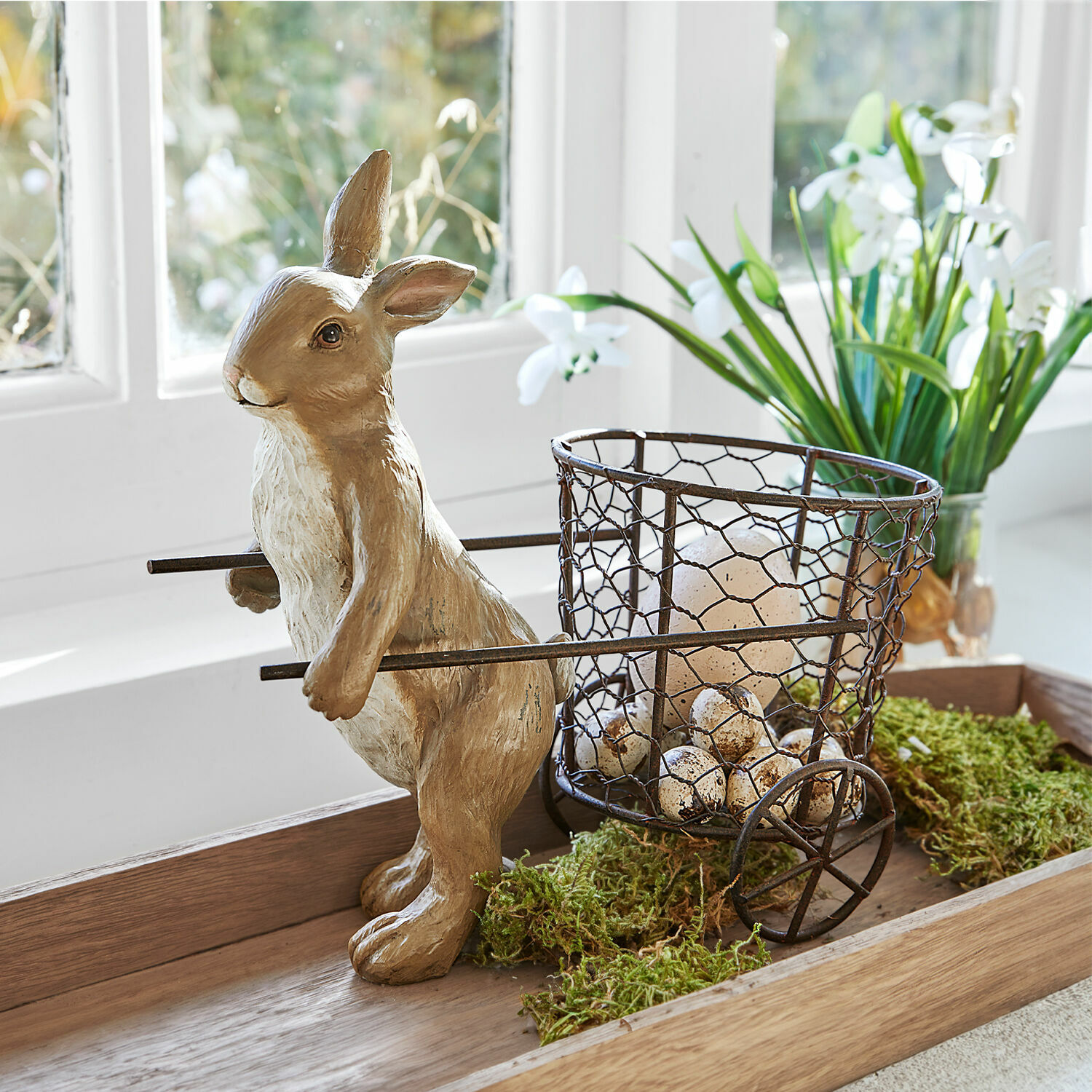 Decoratief resin konijn met metalen mand gevuld met eieren voor lente interieurdecoratie