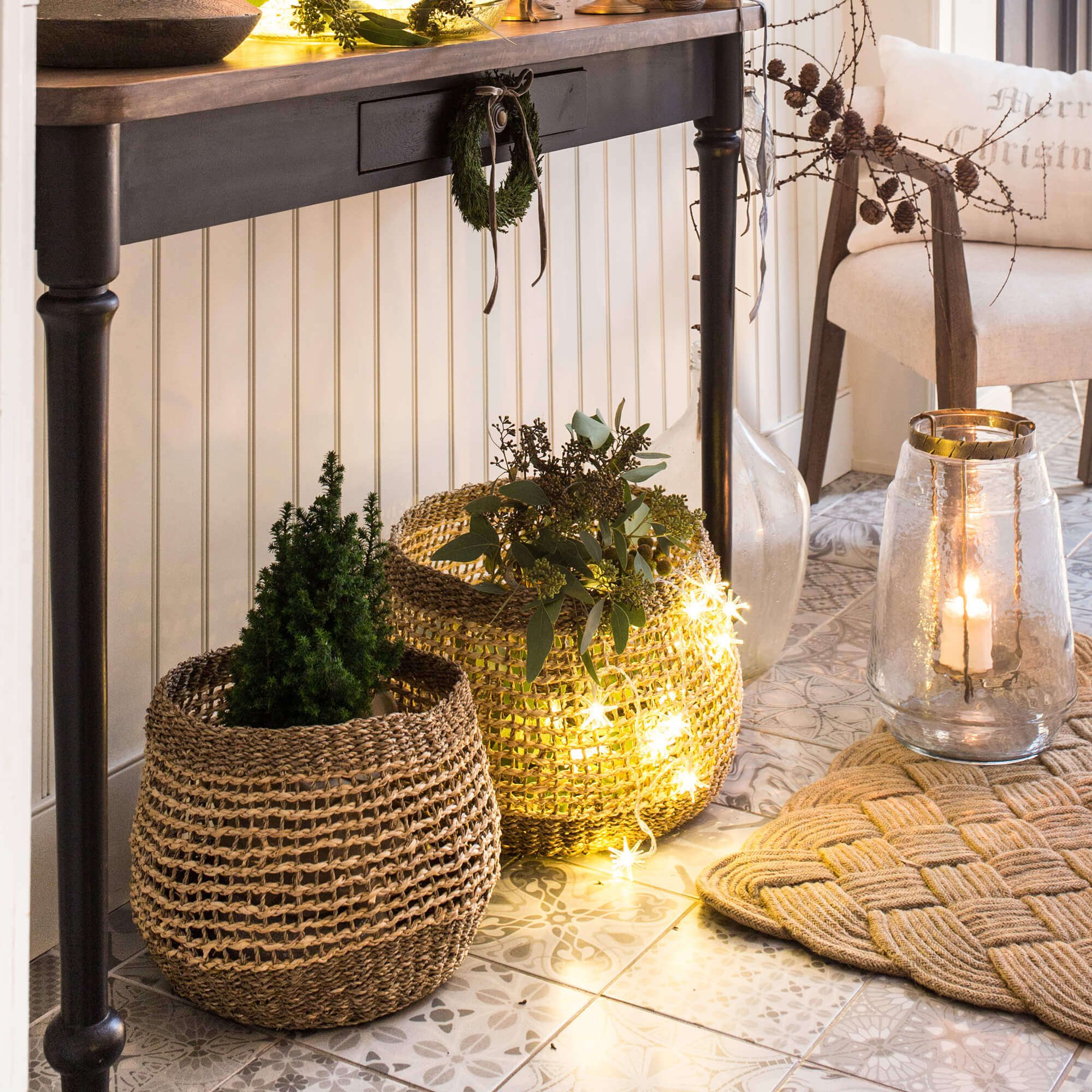 Decoratieve manden van natuurlijk materiaal met groene planten en LED-lichtjes op de vloer