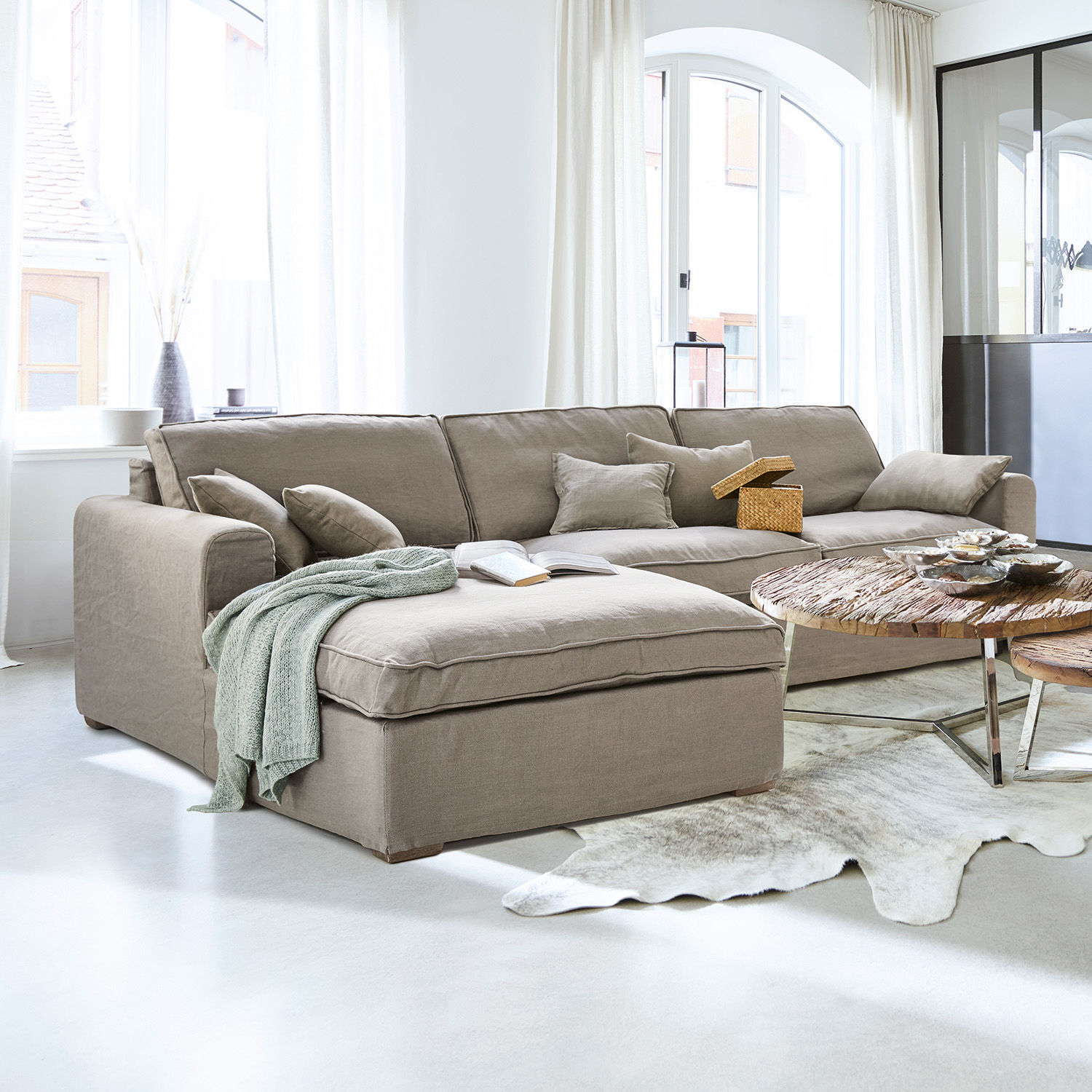 Bank Seaford Beige stoffen hoekbank in lichte woonkamer met houten salontafel en decoraties