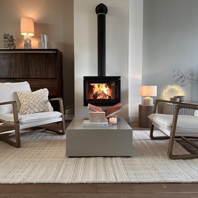 Moderne woonkamer met houtkachel, beige vloerkleed en twee houten stoelen met witte kussens