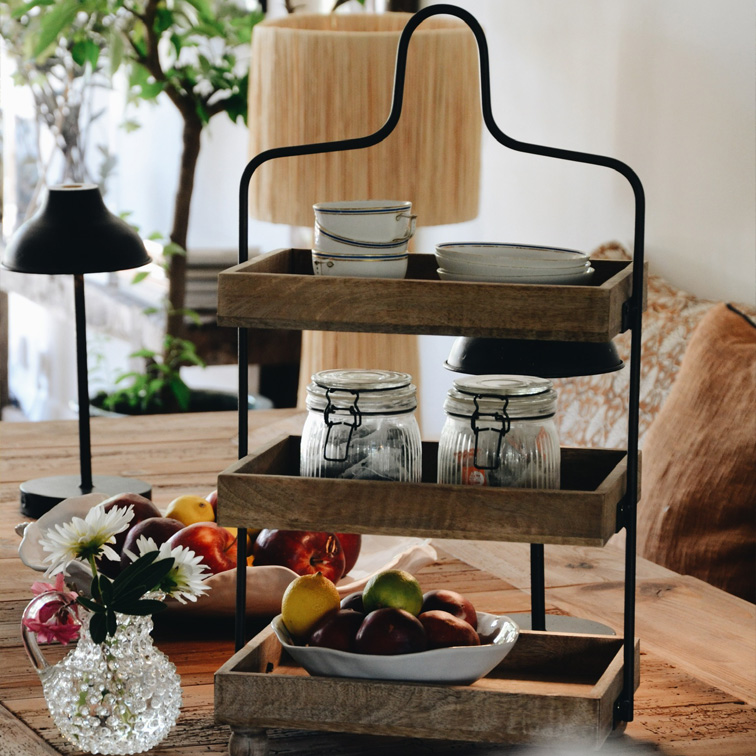 Driedelige houten en metalen etagère met servies en fruit op rustieke eettafel