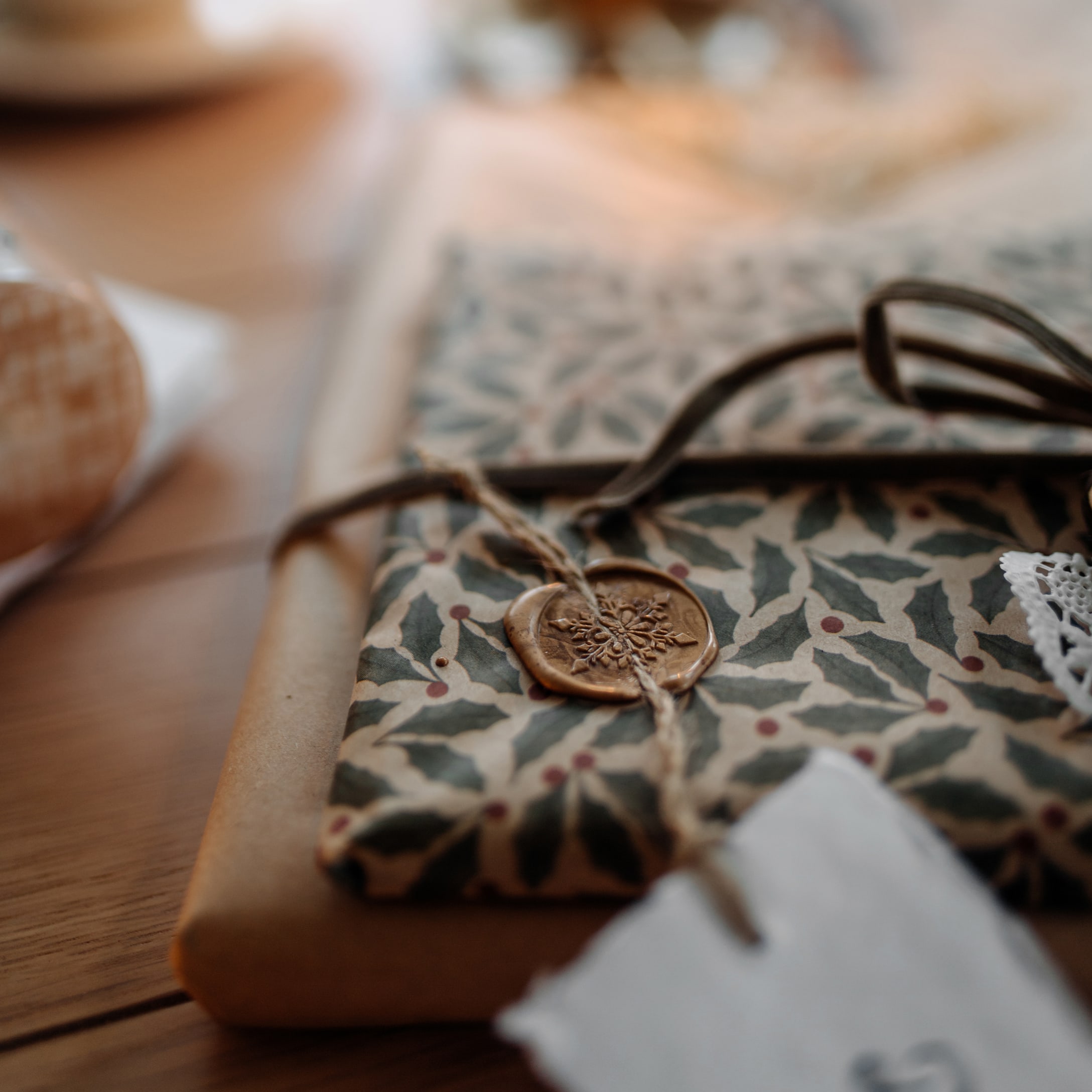 Cadeau verpakt in papier met hulstbladmotief en waszegel aan touw
