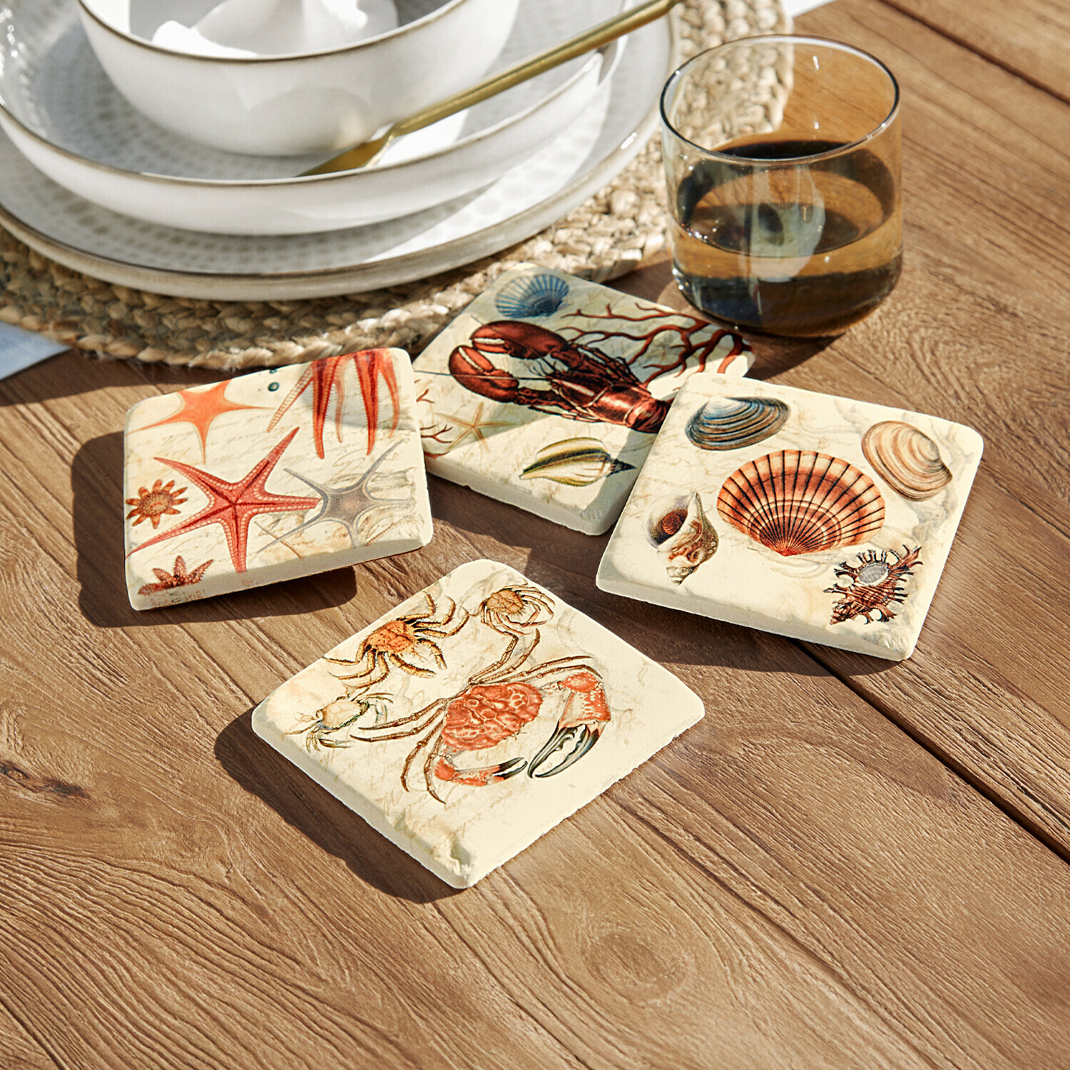 Set van vier keramische onderzetters met maritieme motieven in warme kleuren op houten tafel