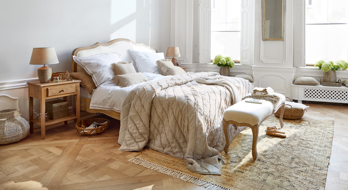 Gezellige slaapkamer in French chic stijl met houten bed en beige beddengoed van natuurlijke materialen