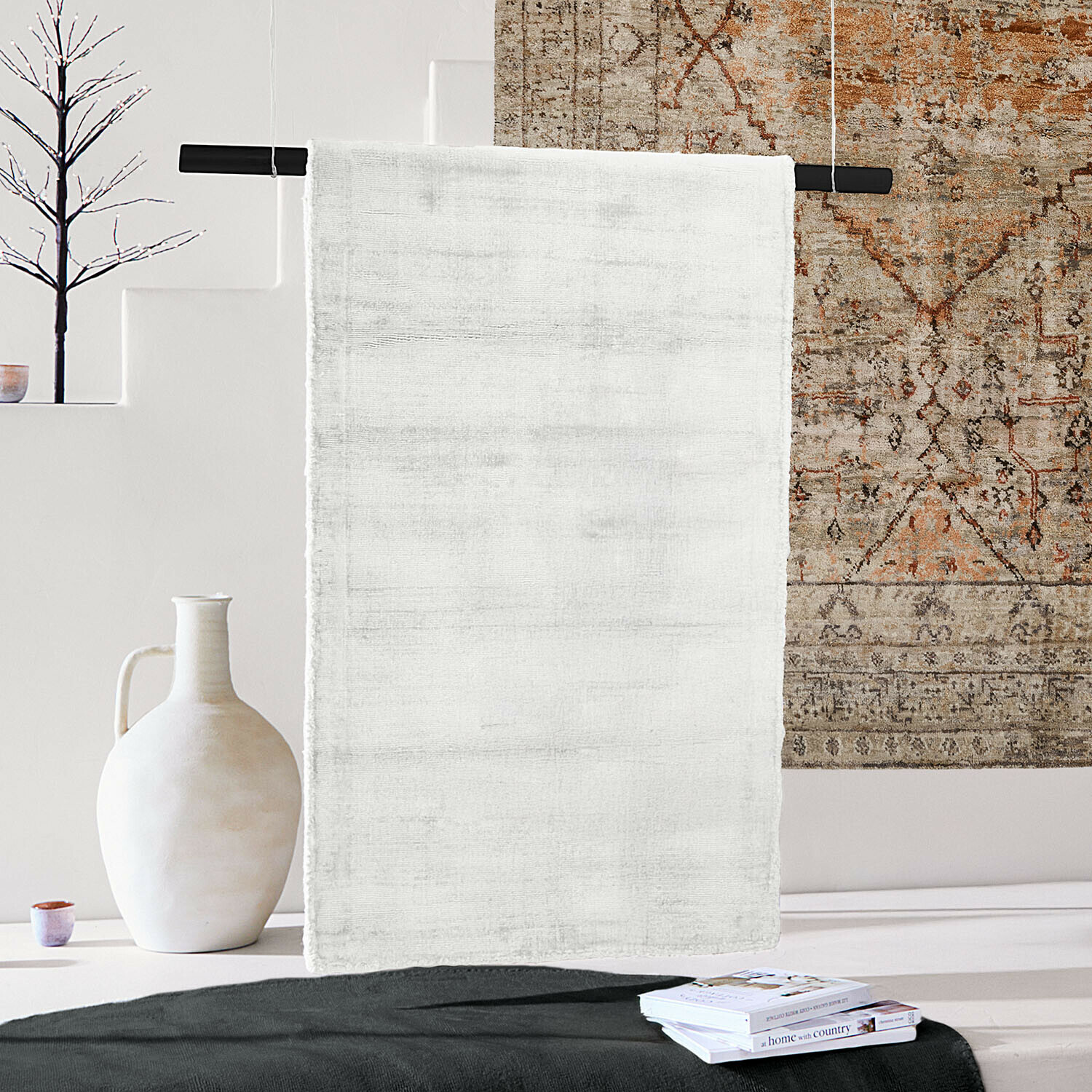 Witte zachte vloerkleed van fijne stof in modern interieur met decoraties en boeken