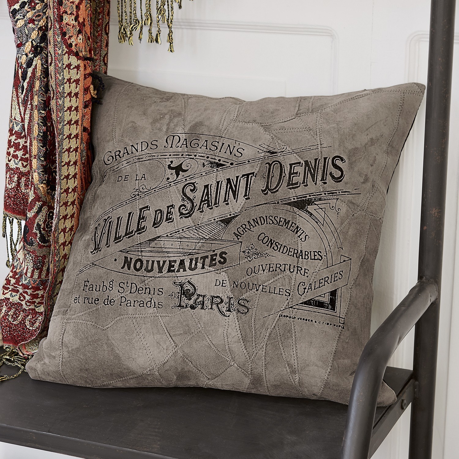 Grijs sierkussen van zacht materiaal met vintage print op zwarte metalen stoel