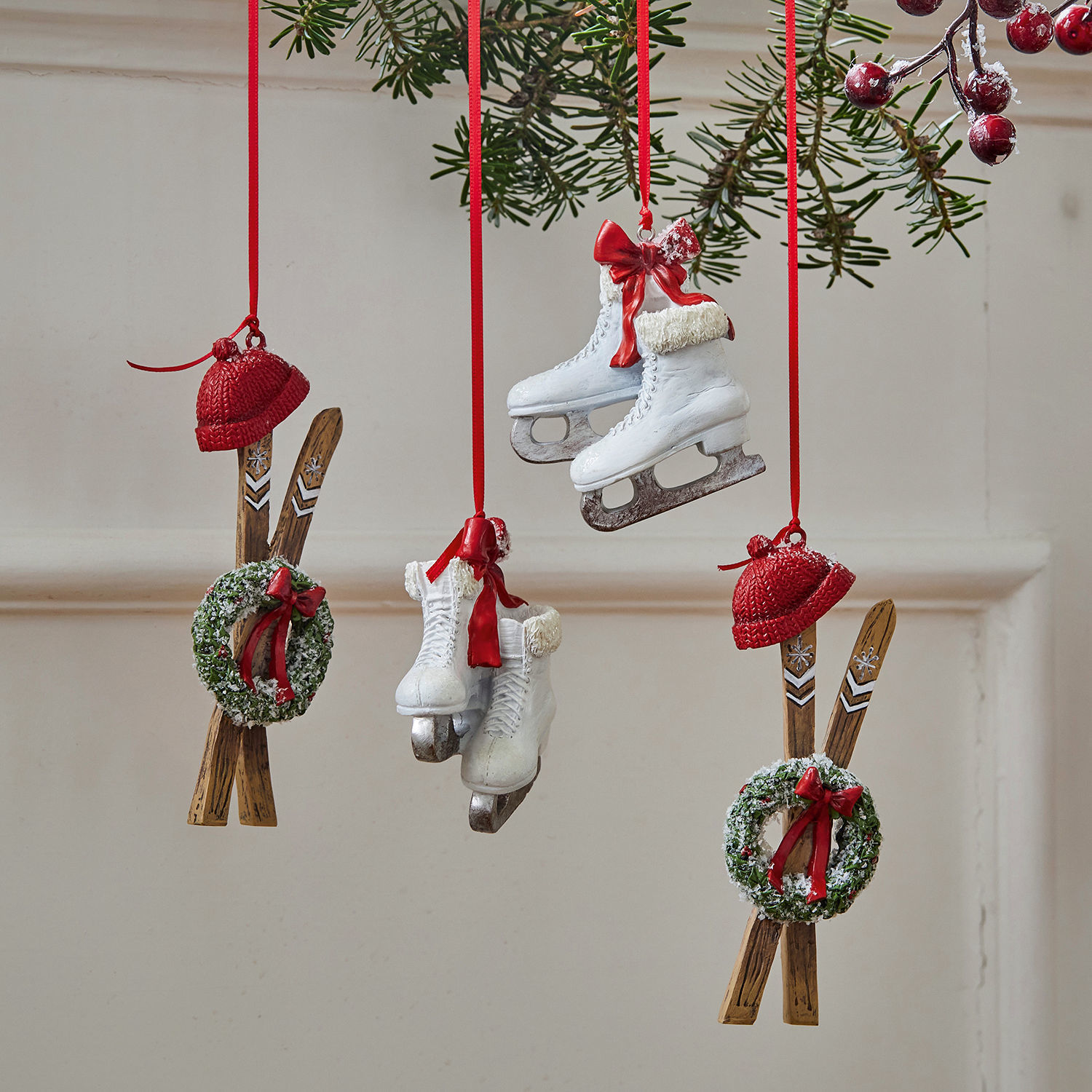 Kerstversiering met witte schaatsen, rode mutsen en groene kransen met rode strikken