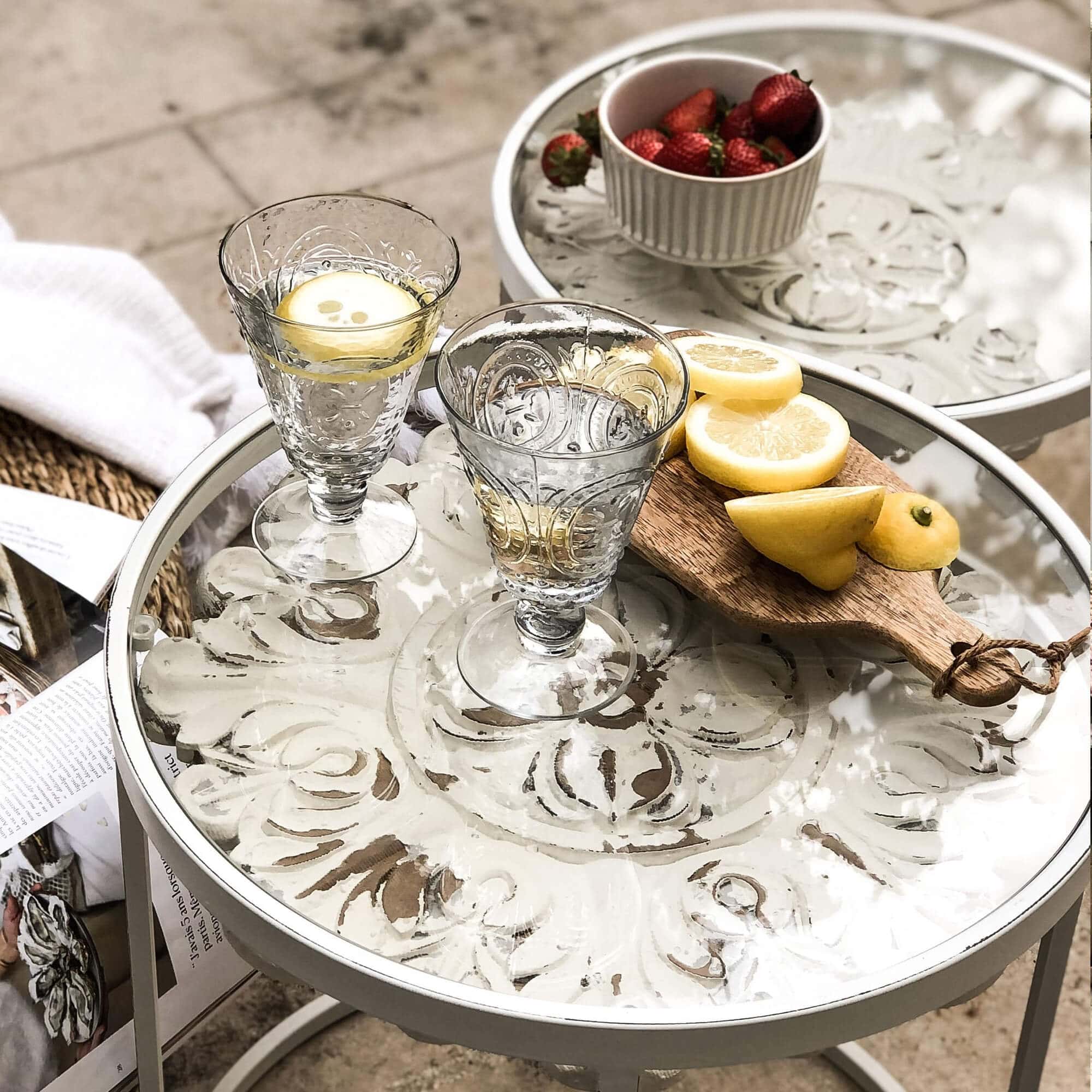Glazen met water en citroen op witte metalen tafel met decoratief blad
