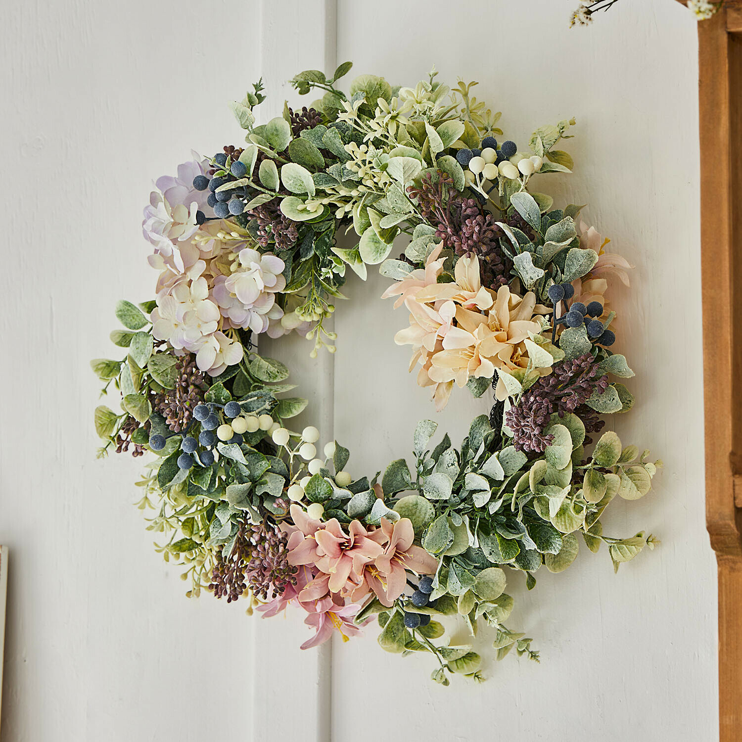 Decoratieve krans met groene bladeren en pastelkleurige bloemen, lente-decoratie voor aan de deur