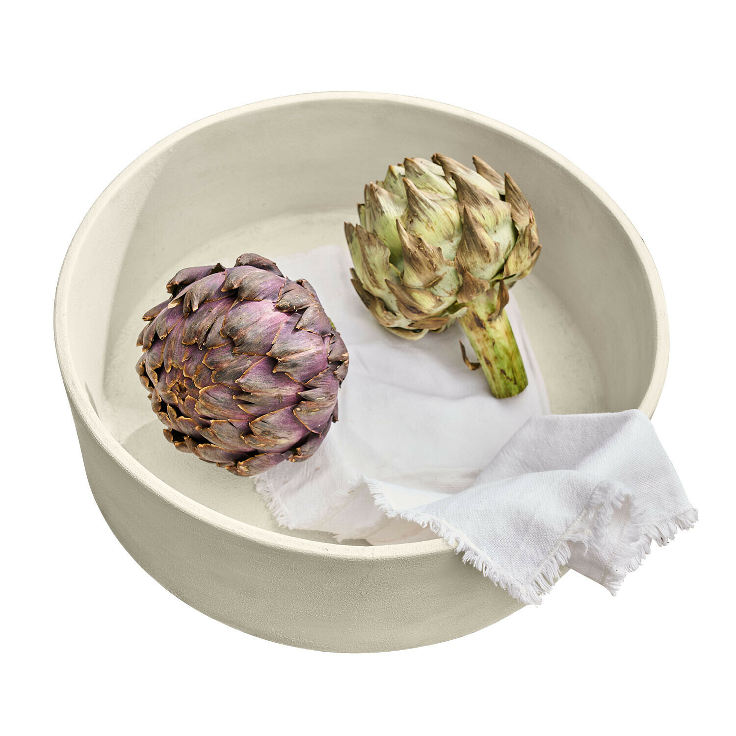 Ronde crème keramische kom met twee artisjokken en een wit doekje erin