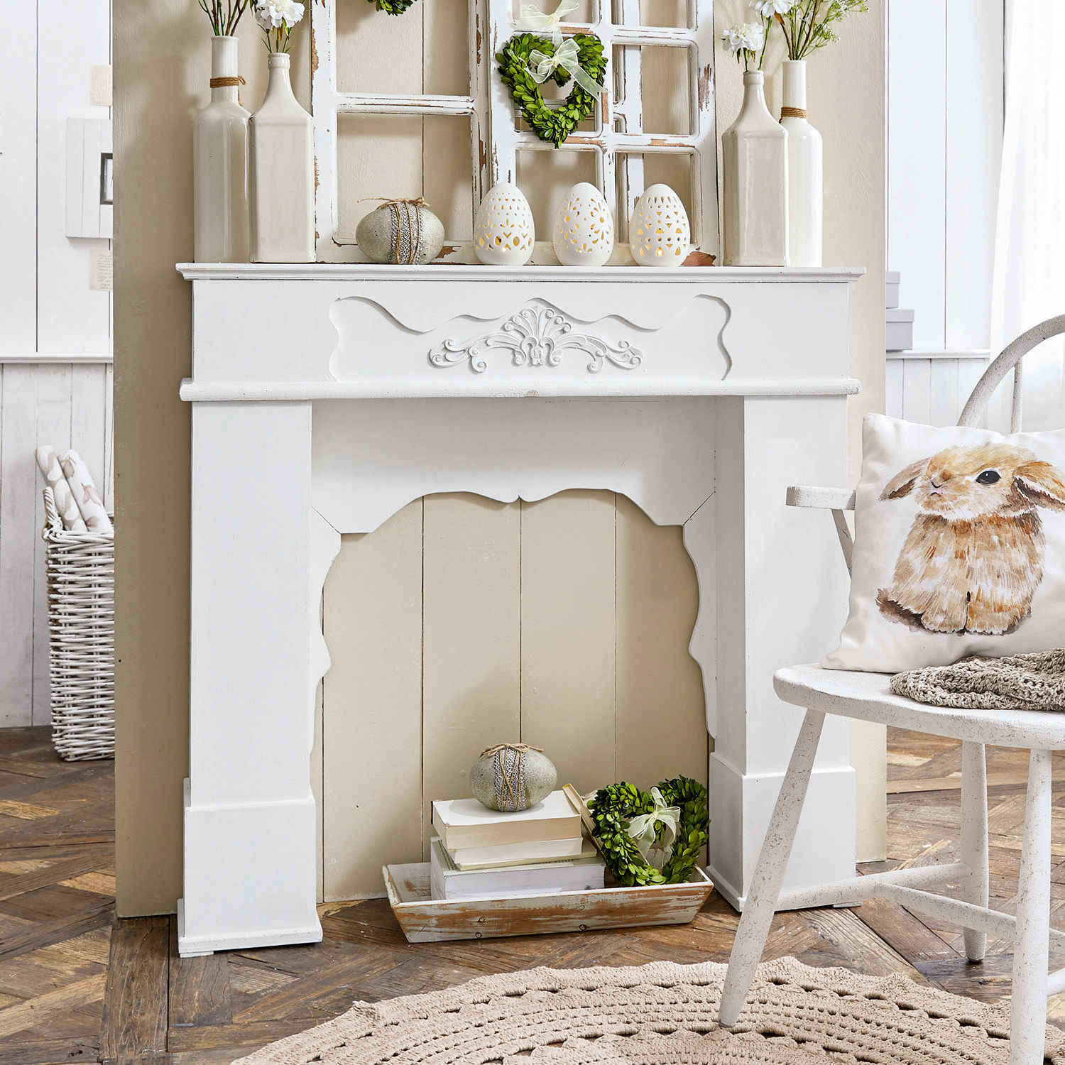 Witte decoratieve schoorsteenmantel met keramische versieringen en kussen met konijnmotief in rustieke kamer