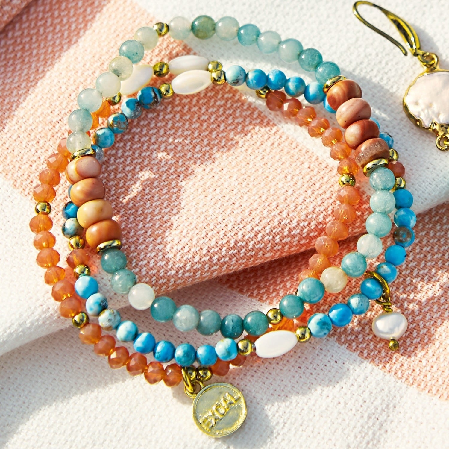 Kleurrijke armband van natuurstenen met gouden elementen op lichte achtergrond, dames sieraden