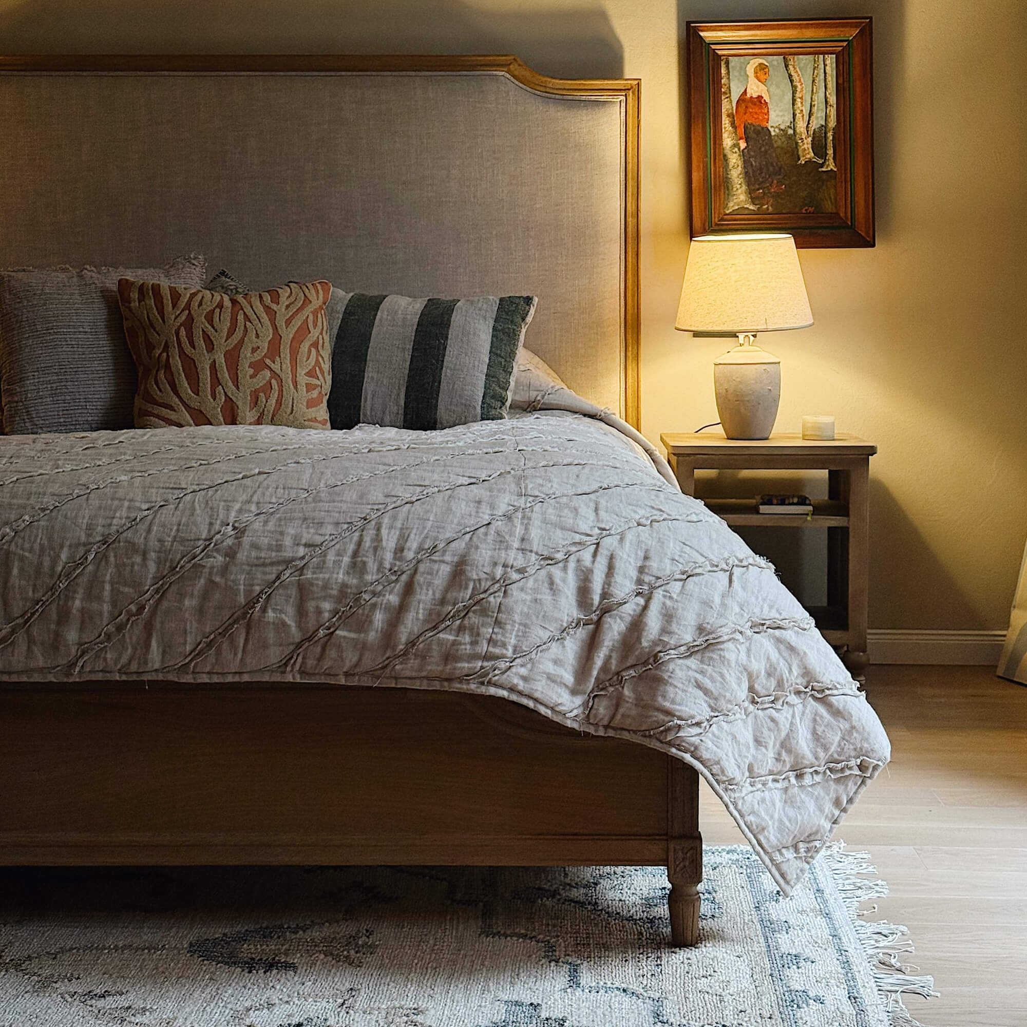 Gezellige slaapkamer met houten bed, beige dekbed en lamp op houten nachtkastje