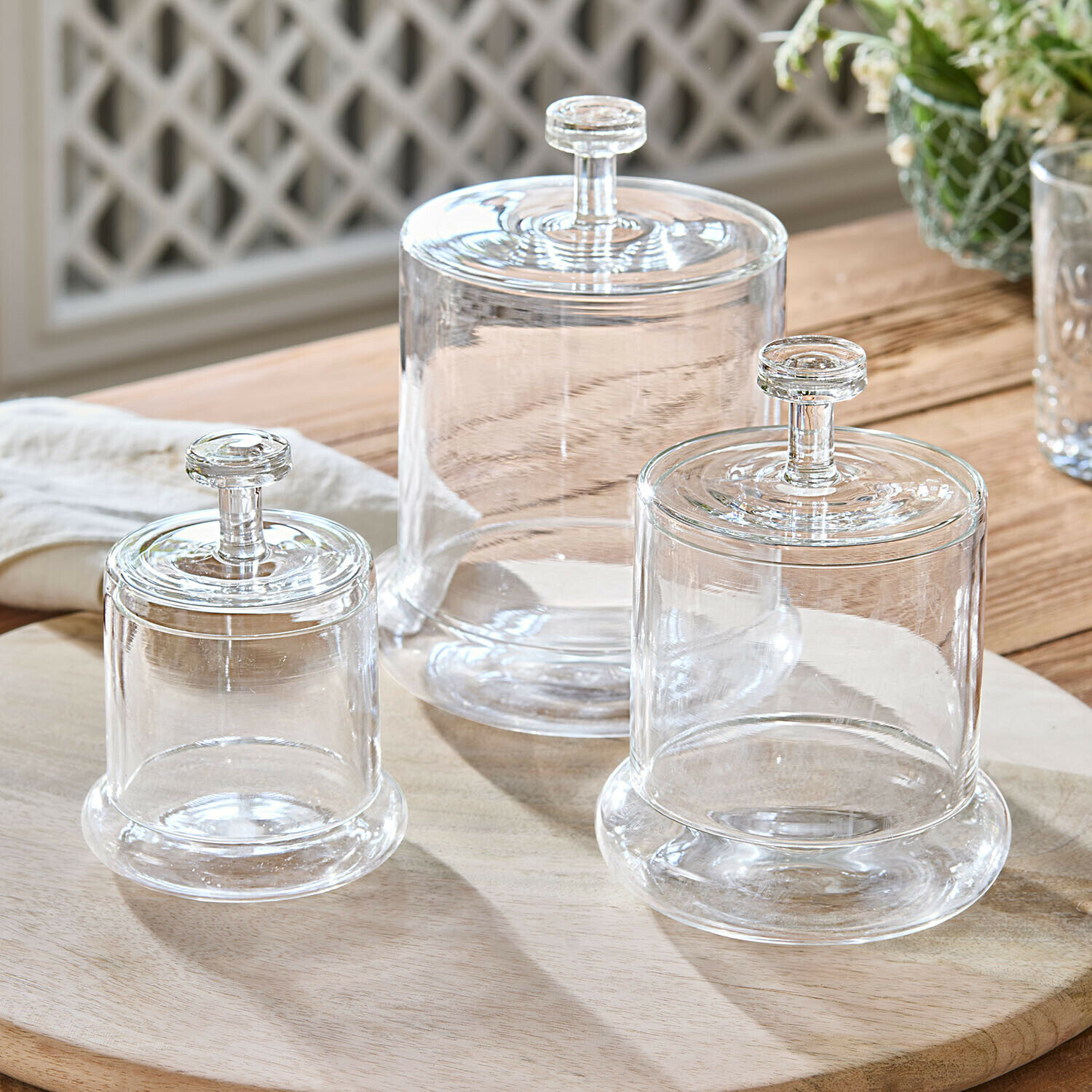 Set van drie doorzichtige glazen potten met deksels op houten plank voor opslag